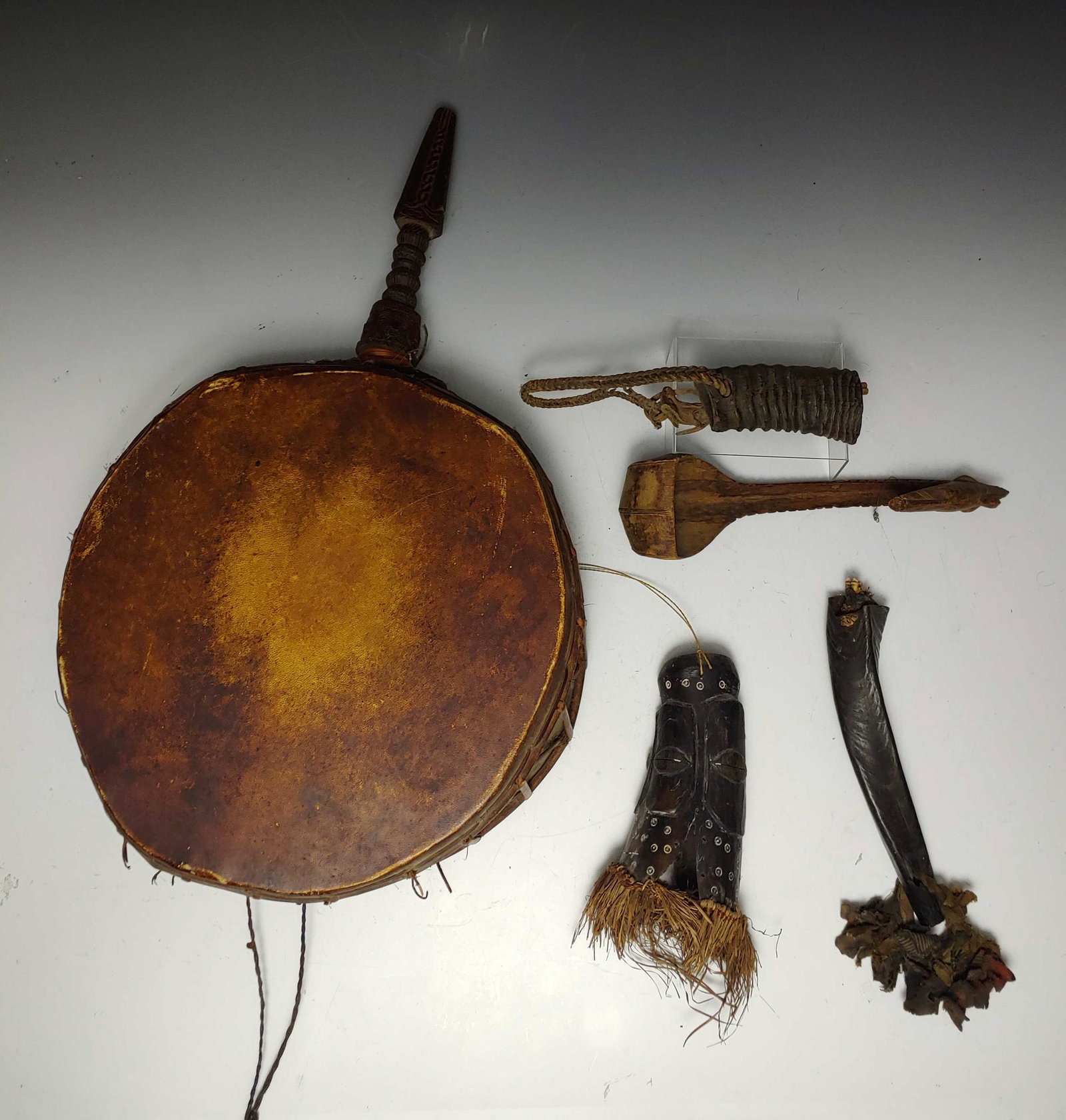 (5) Set of African Ceremonial Instruments: Set of African ceremonial instruments. a) clapper made of hollowed tusk with wooden rod and leather hanger; b) tusk hung on twisted cloth rope with knotted rag fringe, tooth protruding from base; c) h