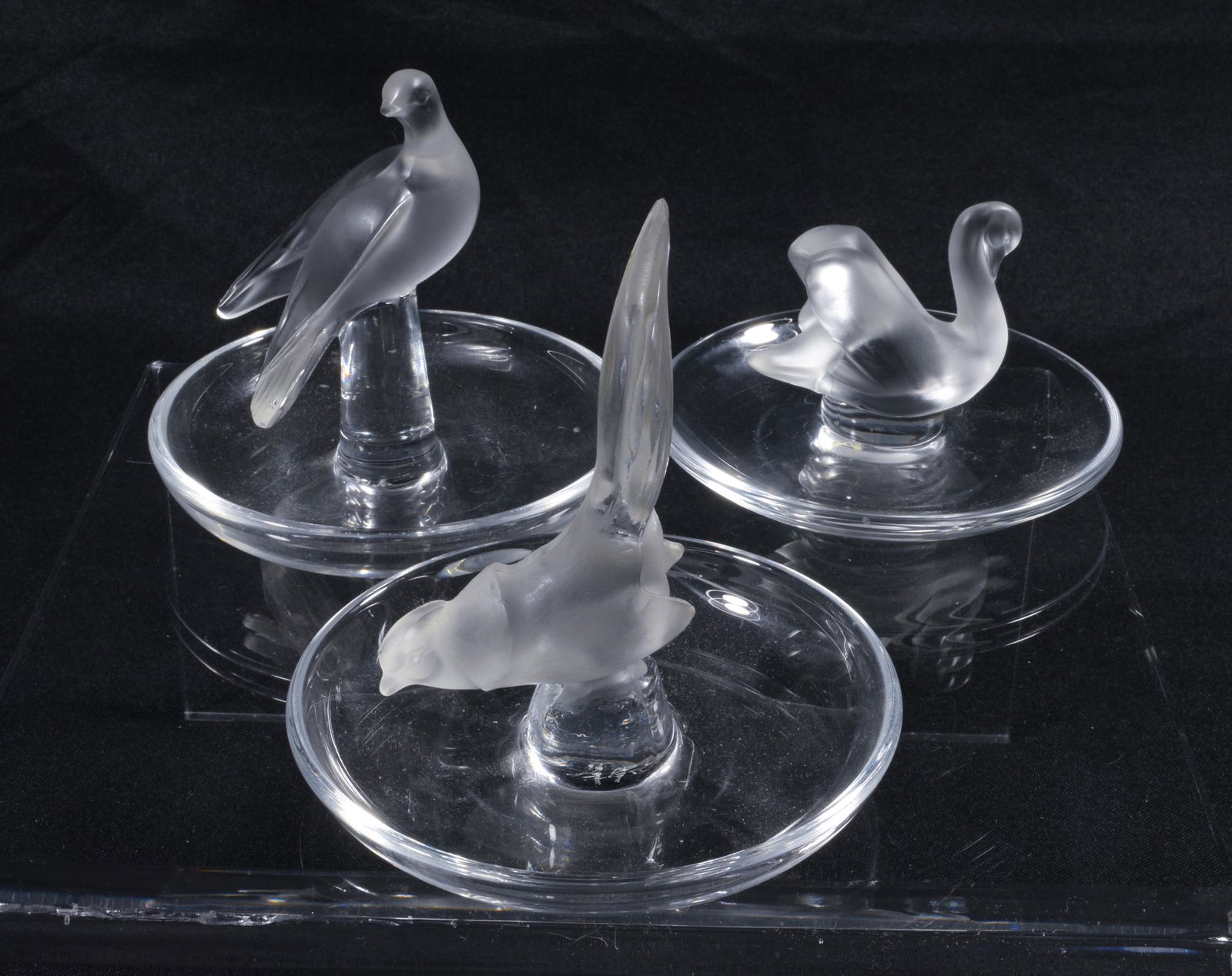 (3) Lalique Bird Pin Trays: (3) Lalique bird pin trays with handles shaped like a pheasant, a swan and a dove. Dimensions are: Largest: 3.875 inches tall X 3.75 inches diameter; 9.8 cm tall X 9.5 cm diameter. All measurements ar