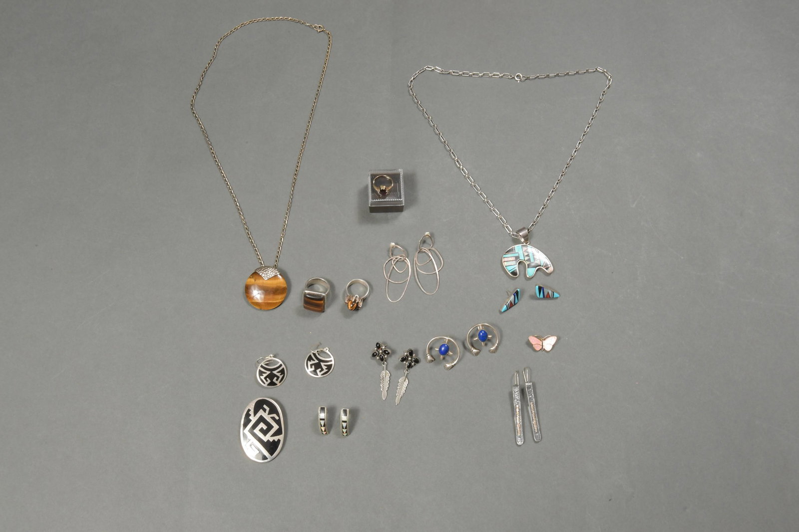 21 Gold & Sterling Jewelry Zuni, Navajo, Mexico: A group of 21 jewelry pieces, includes: a 10k gold & garnet ring, 2 tigers eye rings, a tigers eye pendant, a pair of lapis lazuli earrings, silver earrings, a butterfly pin, a pair of earrings with b