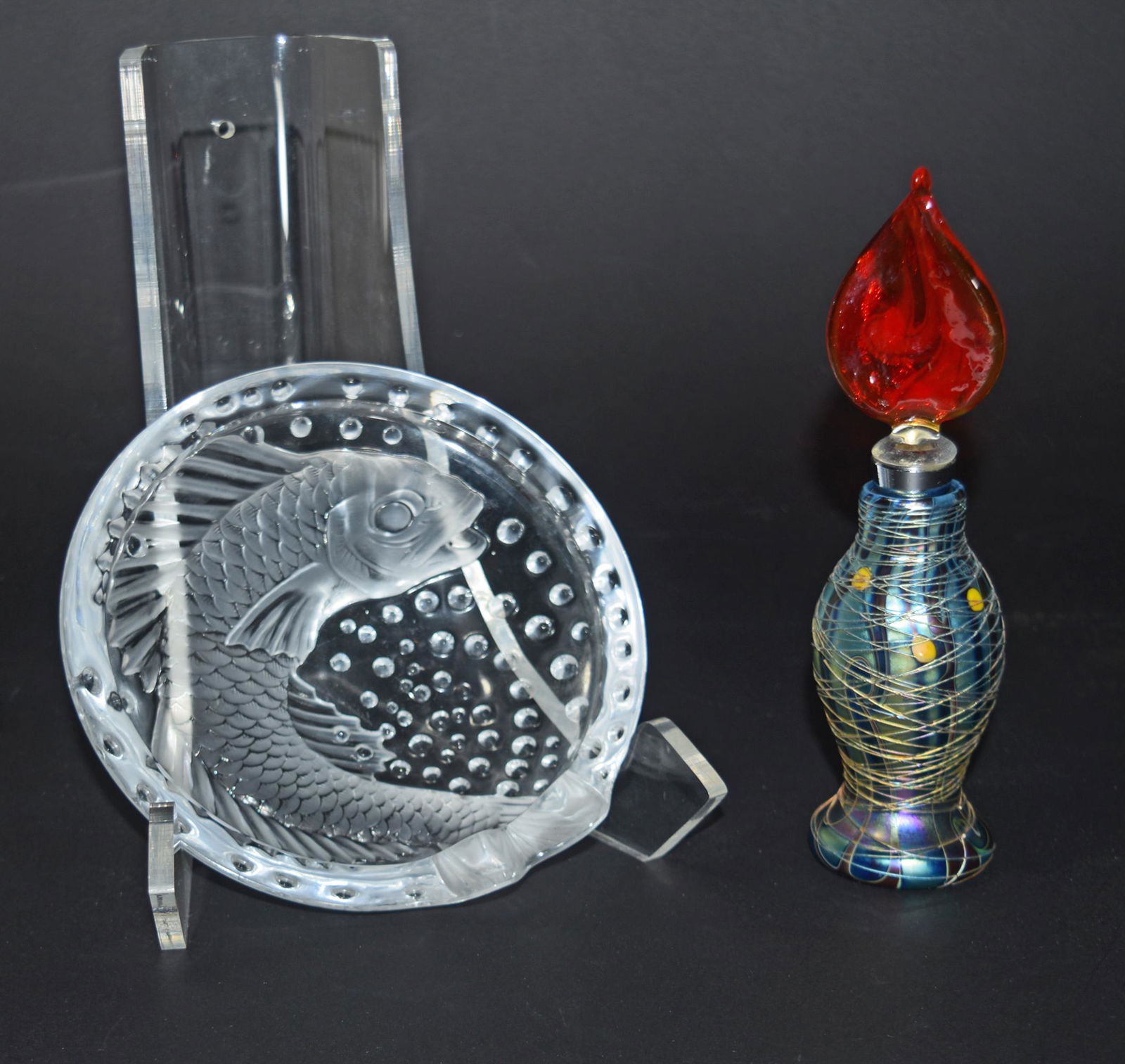 2 Lalique Ashtray & Orient & Flume Perfume: A group of 2 glass items. Includes a P String overlay perfume with a replaced stopper and the original label to bottom, and a Lalique Concarneau ashtray featuring a fish. Dimensions of the ashtray: 6