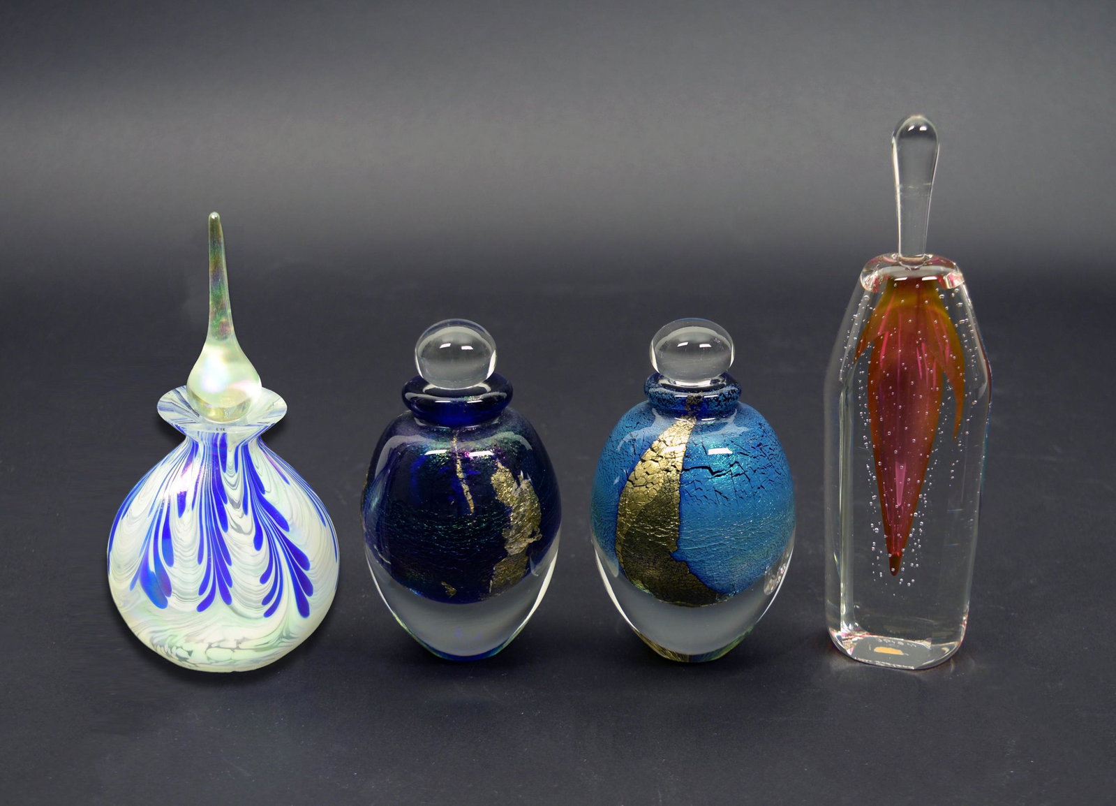 4 Art Glass Perfumes, Eickholt & Fire Island: A group of 4 art glass perfume bottles. Includes one in purple and pink that is unmarked, two by Robert Eickholt both are round, one is purple and the other is blue, they are marked 1990 and 1991. The