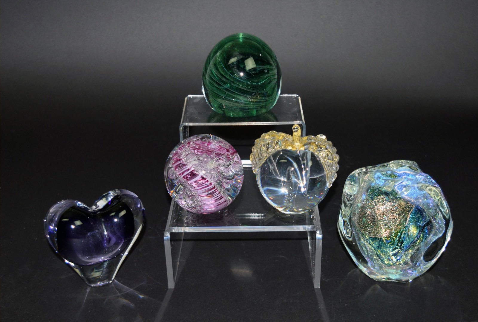 5 Studio Art Glass Paperweights: A group of 5 studio art glass paperweights. Includes: a round green swirled patterned, a pink and bubbles paperweight, an apple-shaped paperweight with gold-toned leaves, a purple heart-shaped weight 