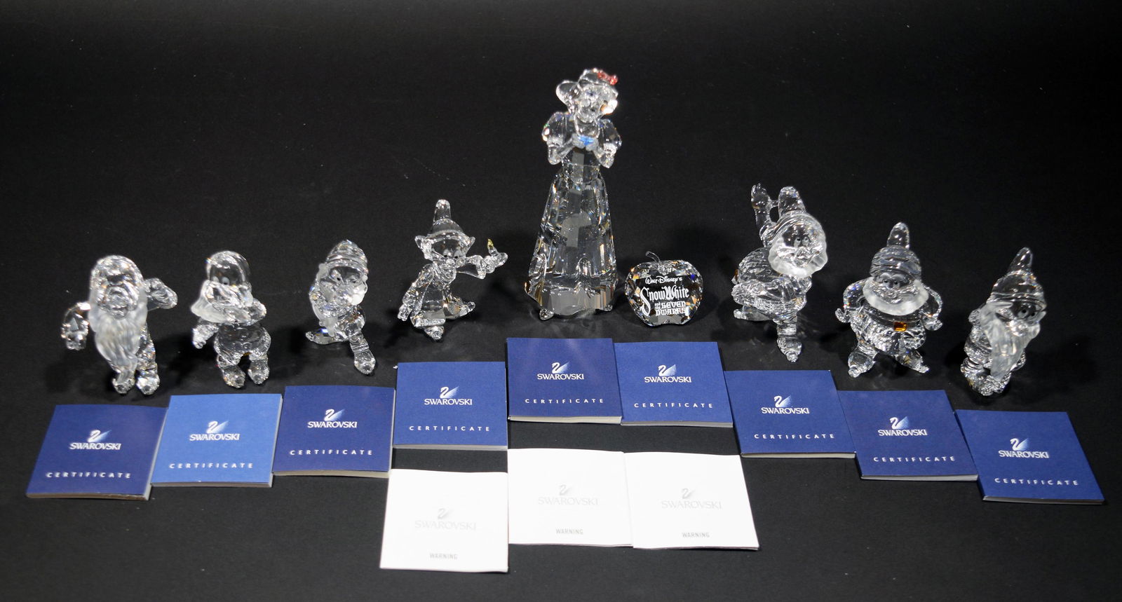 Swarovski, Boxed Snow White & the Seven Dwarfs: Swarovski (Austrian, founded 1895) crystal. Includes figurines of Snow White and the Seven Dwarfs with a title plaque. All dwarves have a yellow buckle besides Bashful. Complete set including title pl