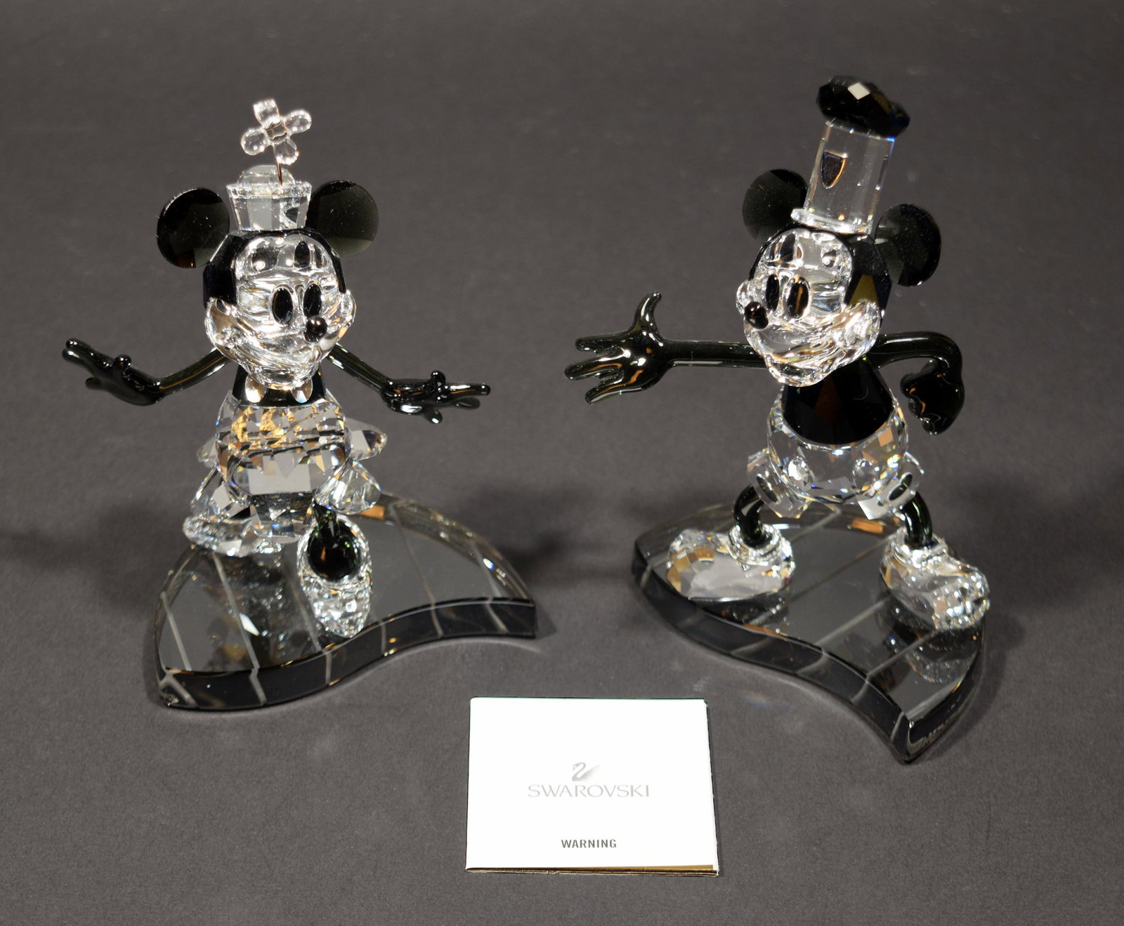 Boxed Swarovski Steamboat Willie, Mickey & Minnie: Swarovski (Austrian, founded 1895) crystal. A pair of figurines of Mickey and Minnie Mouse in the style of Steamboat Willie. The pair come in the original packaging with certificate. Dimensions: 5 1/2