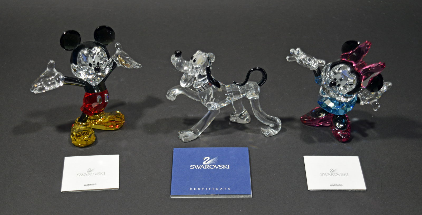 Swarovski, Mickey Mouse, Minnie & Pluto: Swarovski (Austrian, founded 1895) crystal. Includes figurines of Minnie Mouse, Mickey Mouse and Pluto in mid-stride. All come with the original packaging and certificates. Dimensions: 4 1/4 inches ta