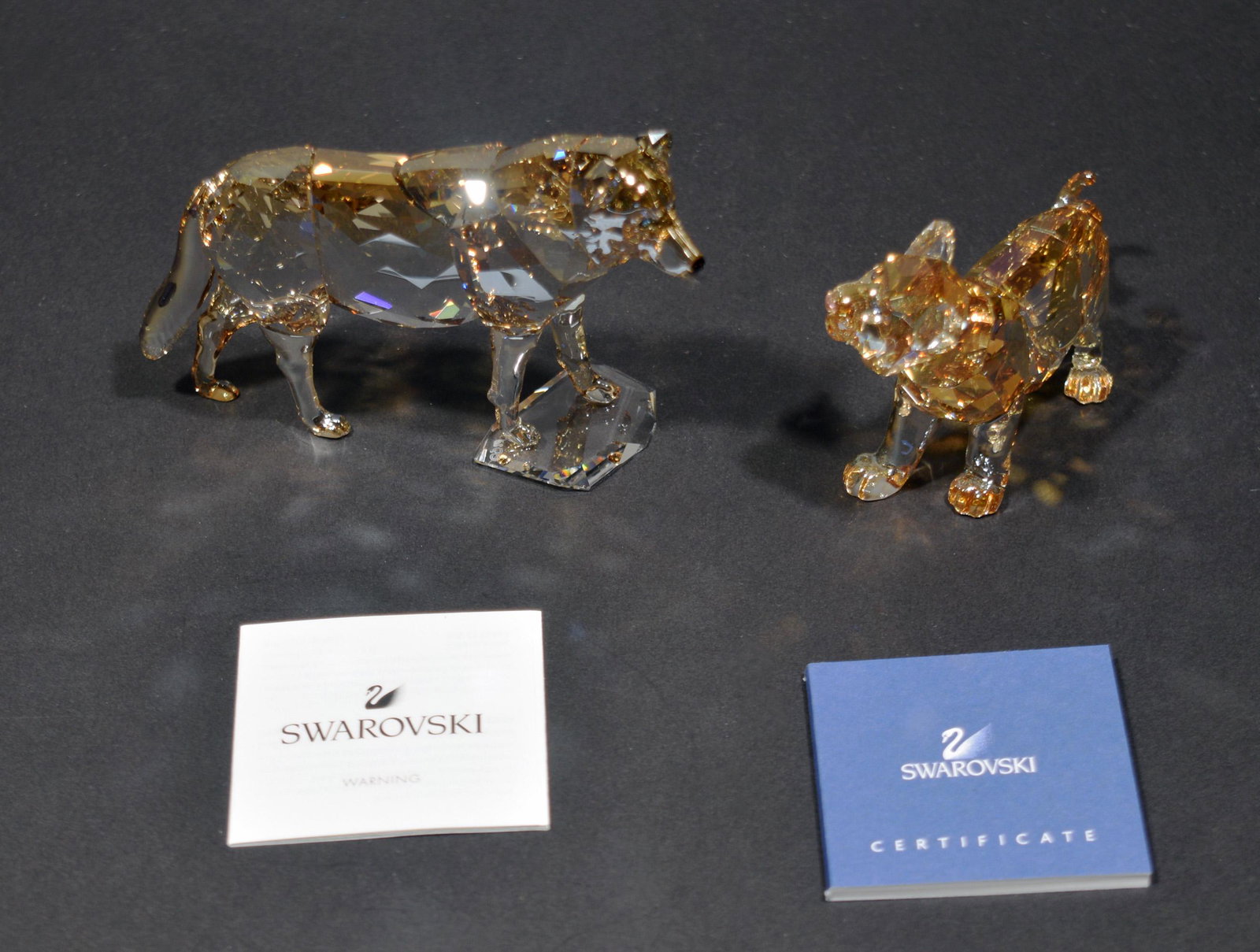 Swarovski, 2 Boxed SCS Figures, Wolf & Tiger Cub: Swarovski (Austrian, founded 1895) crystal. The figurines include a tiger cub dated 2010 and a grey wolf dated 2019. Both figures come with the original packaging and certificates. Dimensions: 2 1/2 i
