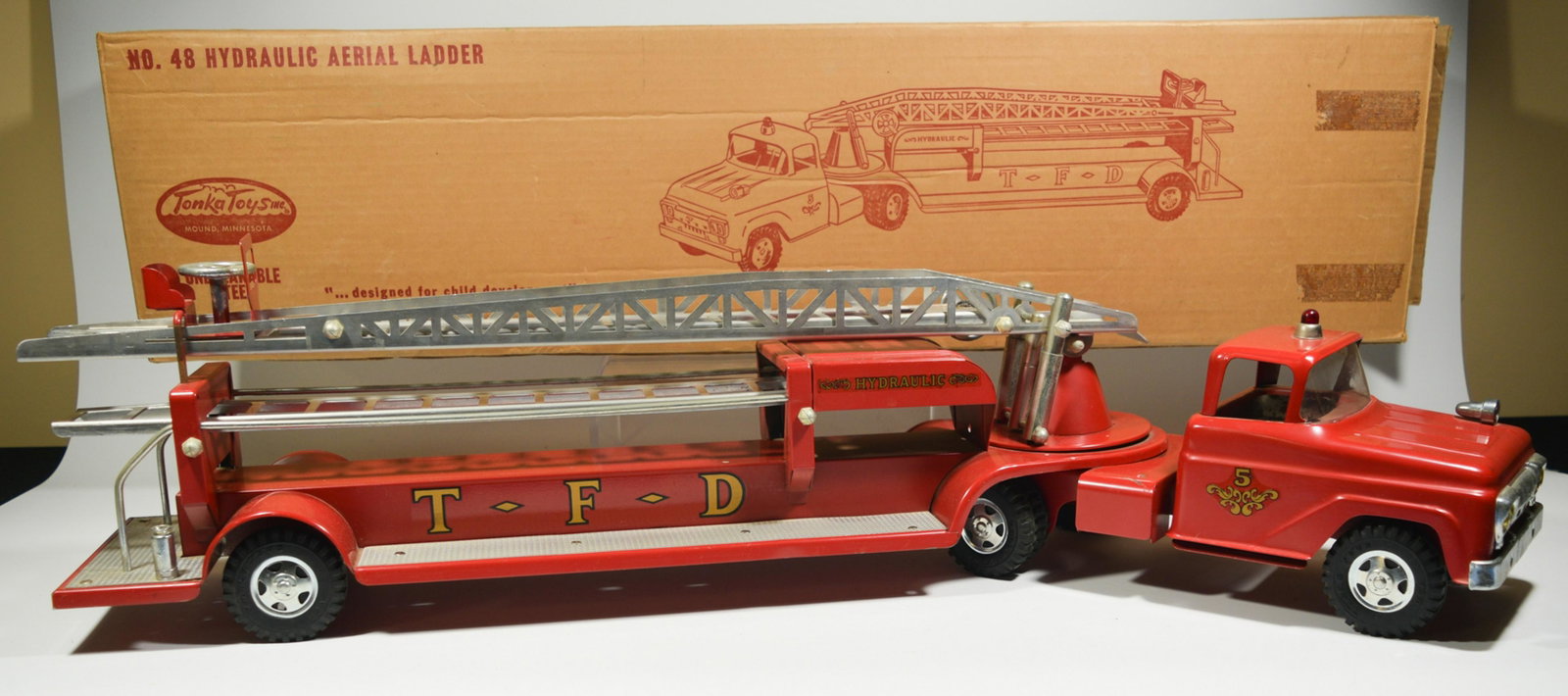 Boxed No. 48 Tonka Hydraulic Aerial Ladder Truck: A Tonka hydraulic aerial ladder truck, the truck features a '5' on either side, the ladder attachment features 'Hydraulic' and 'T. F. D.' on either side. Includes the original box. Dimensions: 8 1/4 i
