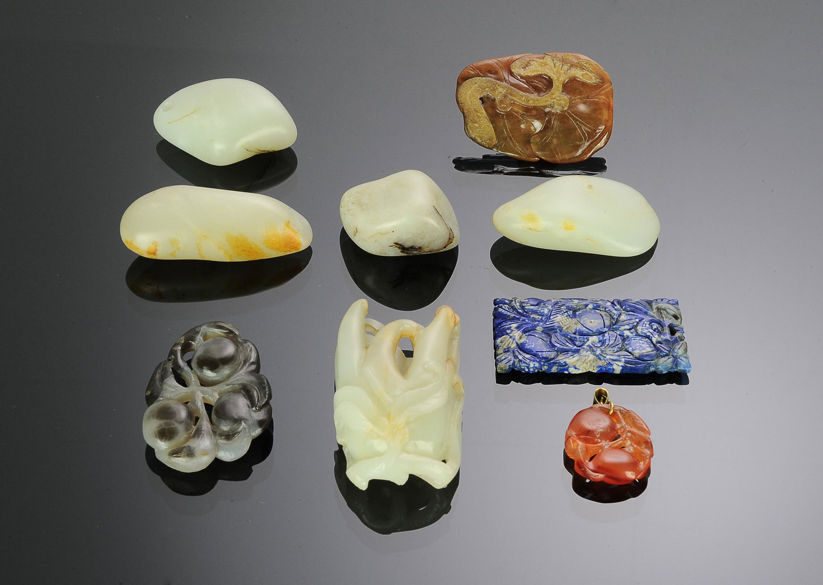 9 Chinese Stone & Jade Carvings, 18-19th Century: A group of 9 jade and stone carvings dating from the 18th to the 19th century. The jade includes: a carving of a Buddha's Hand fruit, 4 smooth white jade toggles. Also includes: a jadeite plaque featu