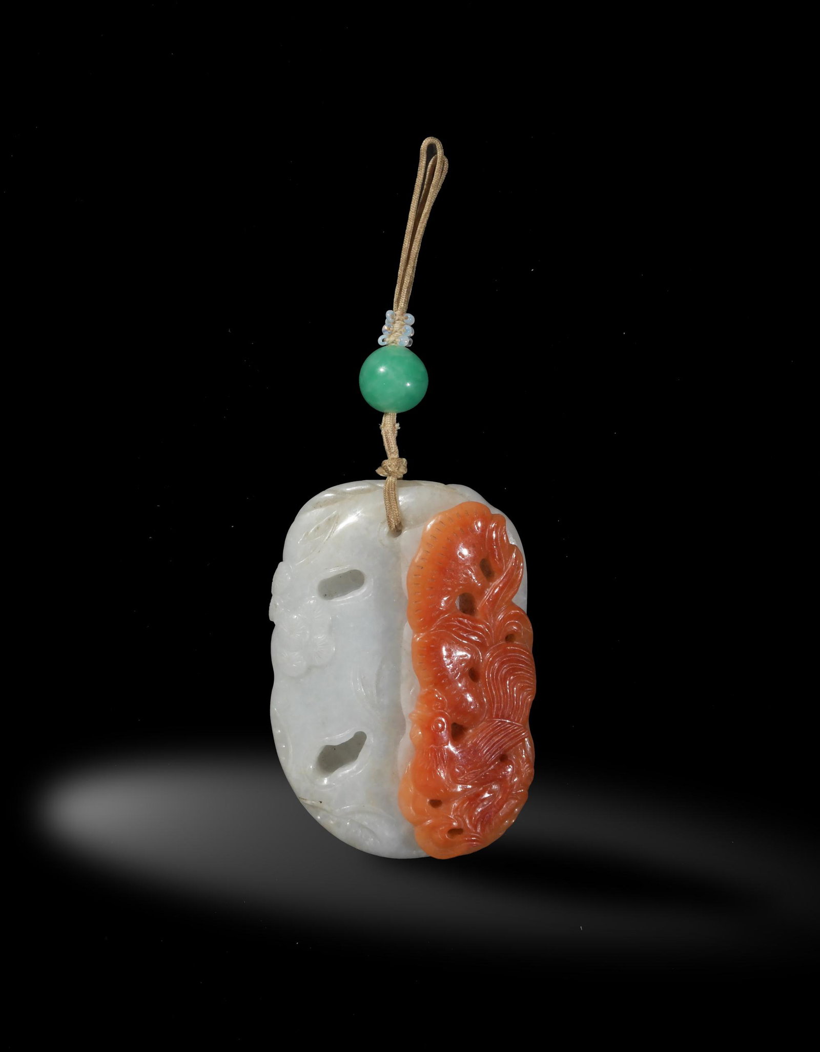 Jadeite Pendant Carved with Flowers & Bird, 19th: A Chinese jadeite with skin pendant dating from the 19th century. The pendant features trees, flowers, and a bird. The bird is carved from the skin. The jadeite is pierced at the top and stung on a lo