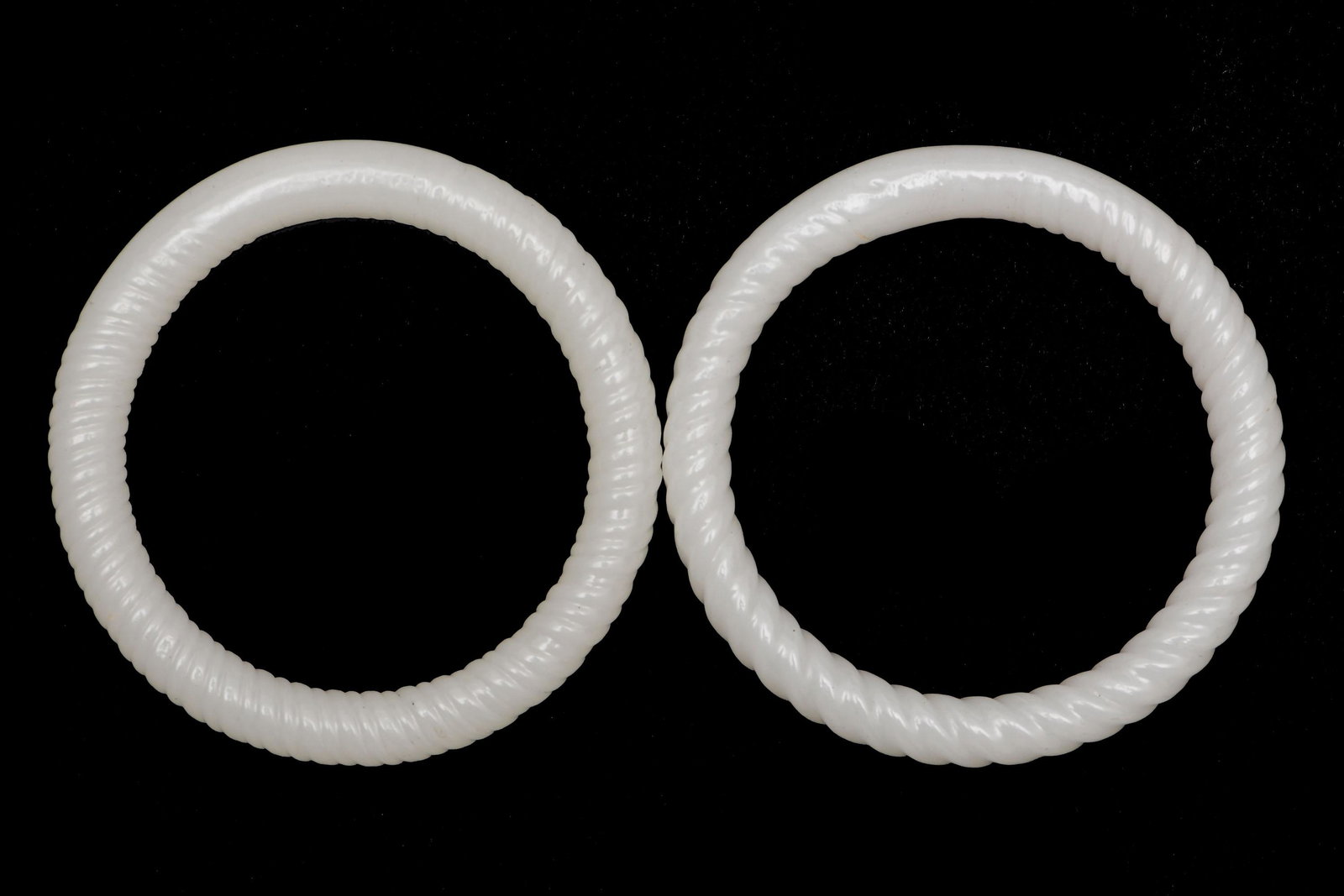 Pair of Chinese Peking Glass bangles, 18-19th Century: A pair of Chinese white Peking glass twined bangles dating from the 18th to the 19th century. Dimensions: 2 1/2 inches interior diameter X 3/8 inch wide; 6.4 cm interior diameter X 1 cm wide. All meas
