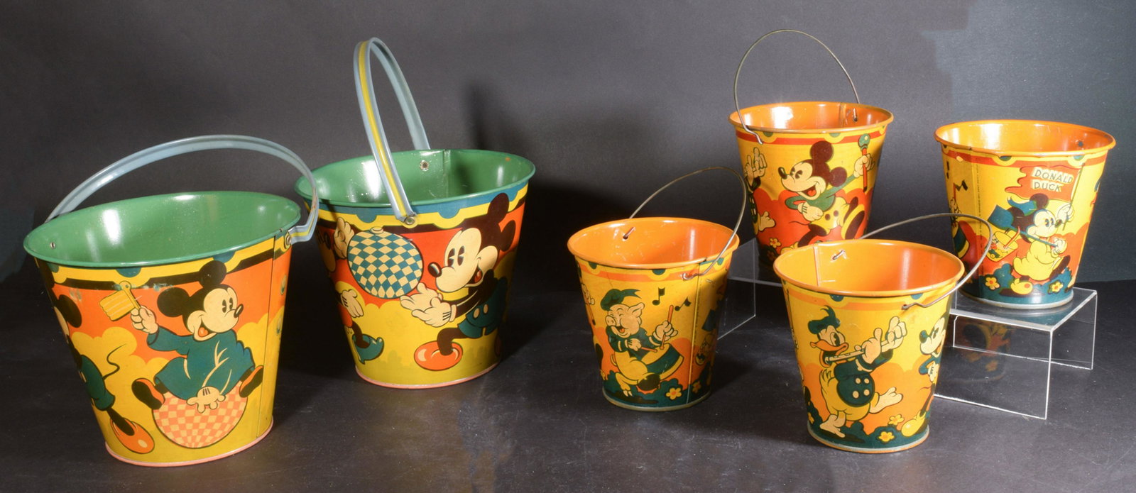 Six NOS 1930s Disney Happynak Sand Pails: Six unused old store stock 1930s Happynak Disney Sea Side sand pails. Four smaller no. 7 pails with Mickey Mouse, Donald Duck, etc. and two larger No. 12 pails with Mickey, Minnie and a nephew. Dimens