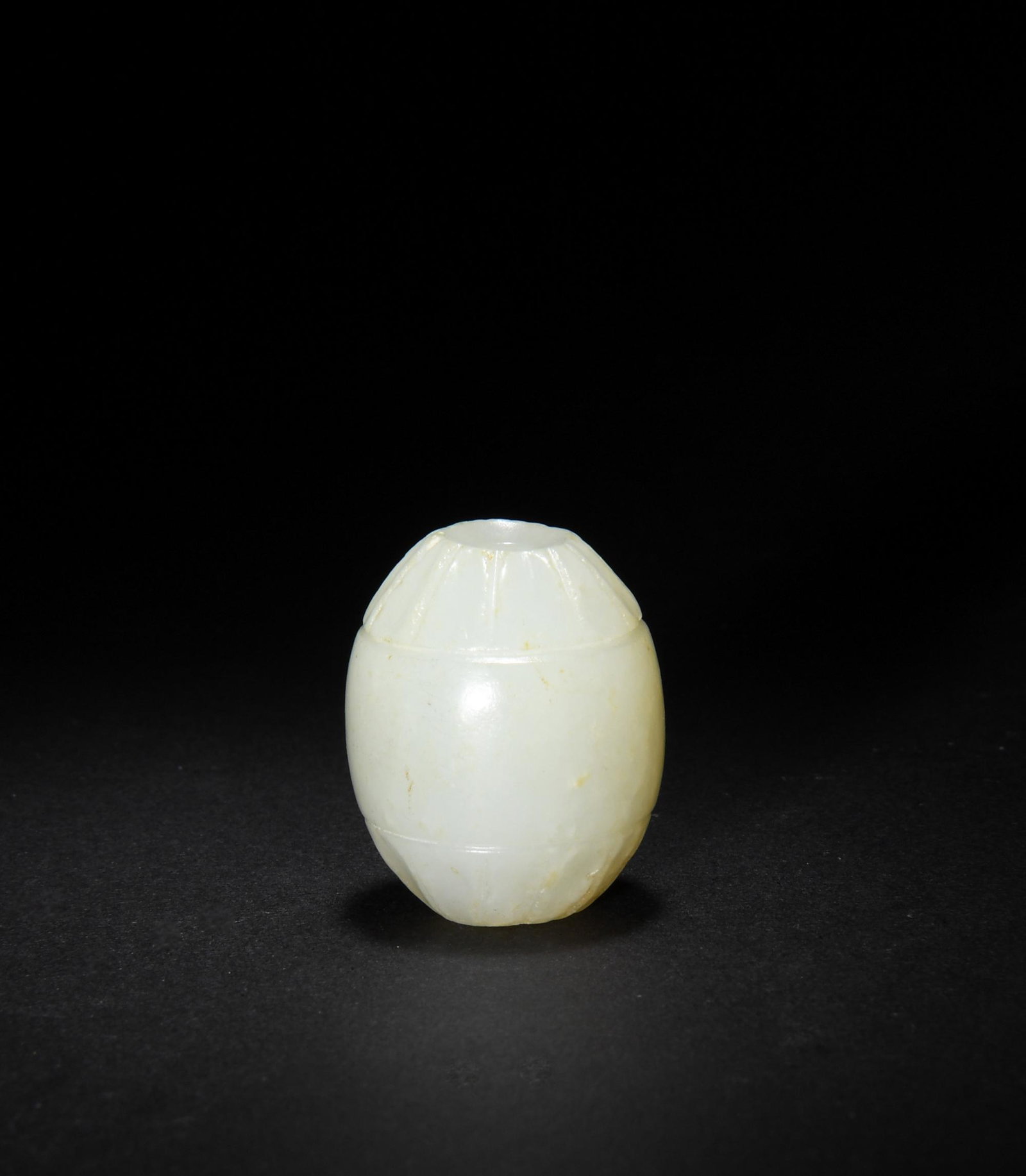Chinese White Jade Carved Bead, Ming: A Chinese white jade carved oval bead dating to the Ming dynasty. The bead features a floral motif at either end. Dimensions are: 1 1/8 in. tall 1 in. wide; 2.6 cm tall X 2.5 cm wide. All measurements