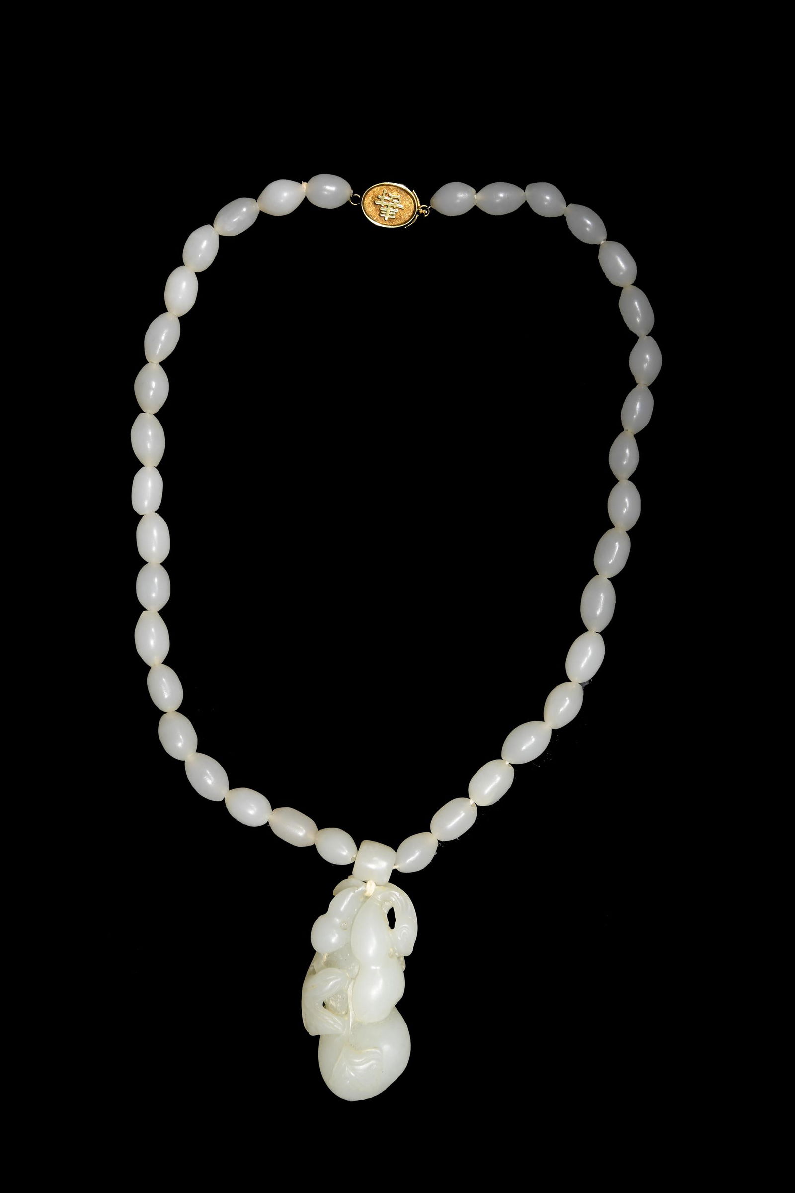 Chinese White Jade Necklace, 19th Century: A Chinese white jade necklace dating from the 19th century. The necklace features a white jade toggle pendant that depicts a trio of hulu gourds and a bat. There is a Shou character on the clasp. Dime