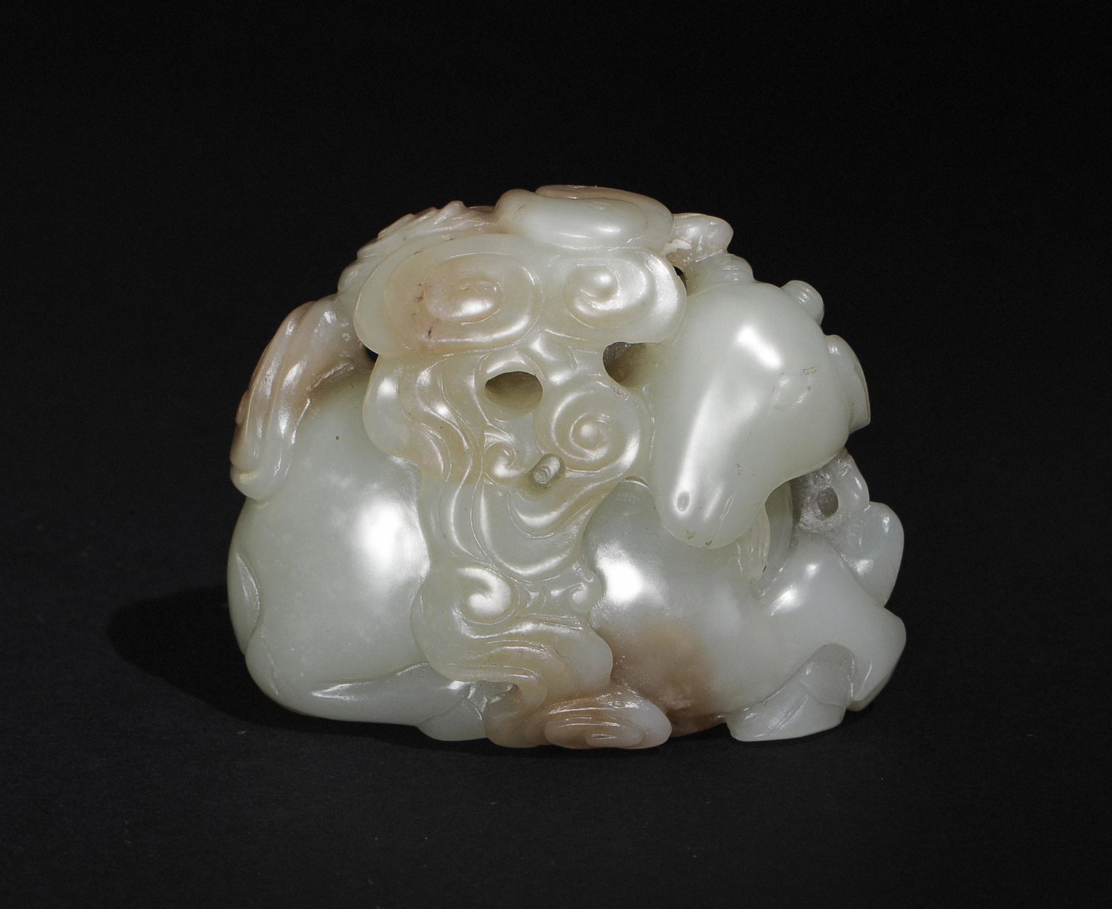 Chinese Jade Carving of Goat, 17-18th Century: A Chinese jade carving dating from the 17th to 18th centuries. The carving depicts a goat lying down amongst lingzhi and swirling clouds. At the top of the clouds is a yin yang symbol. Dimensions are: