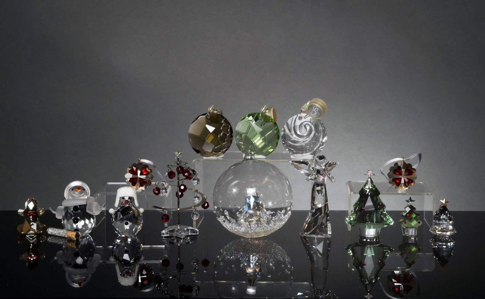 Swarovski, 14 Boxed Crystal Christmas Pieces: Swarovski (Austrian, founded 1895) crystal. A group of Christmas pieces including: 2 snowmen, a bamboo sun ornament, an Air sun ornament, a suncatcher ornament, an angel ornament dated 2013, a rocking