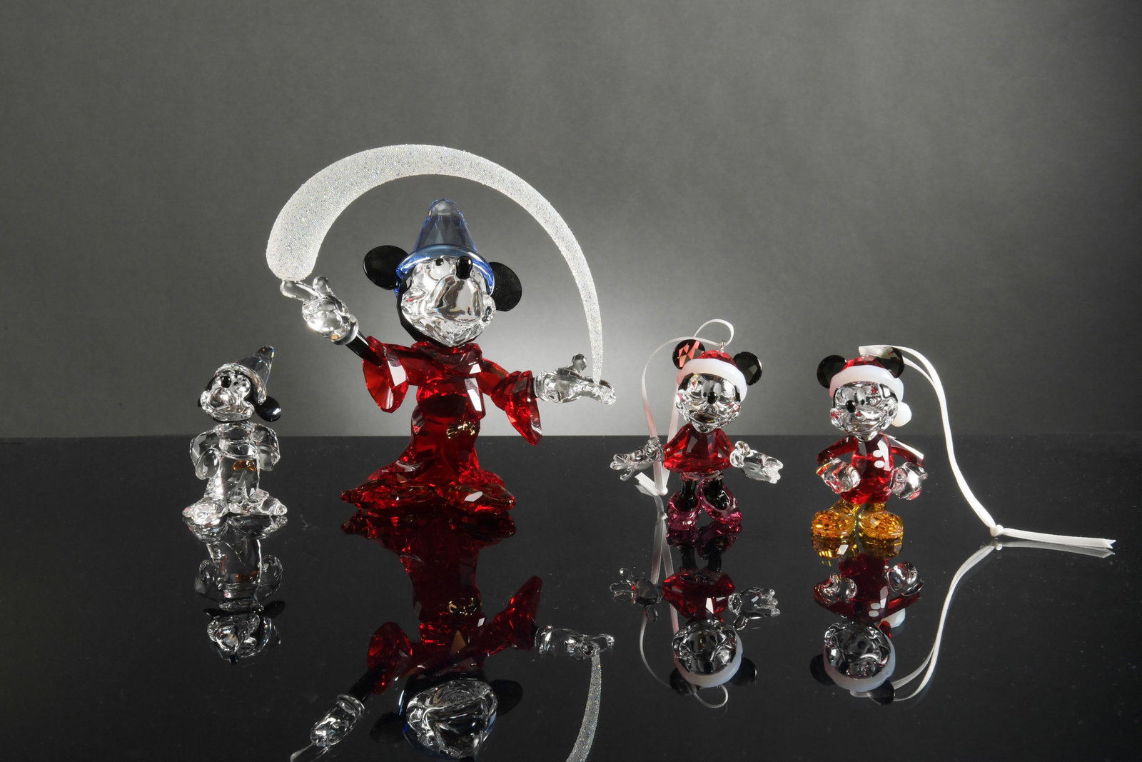 Swarovski, 4 Boxed Disney including 2 Sorcerer Mickey: Swarovski (Austrian, founded 1895) crystal. A group of 4 Disney items. Includes: a small Sorcerer Mickey; a Mickey Mouse Christmas ornament; a Minnie Mouse Christmas ornament; and a large Sorcerer Mic
