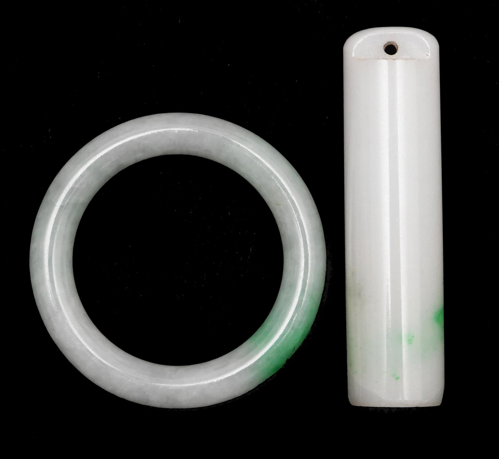 Chinese Jadeite Ring and Cylinder, 19th Century: A Chinese jadeite ring and carved cylinder dating from the early 19th century. Dimensions: 2 1/2 inches tall X 5/8 inches wide; 6.4 cm tall X 1.6 cm wide. All measurements are approximate. Condition: 