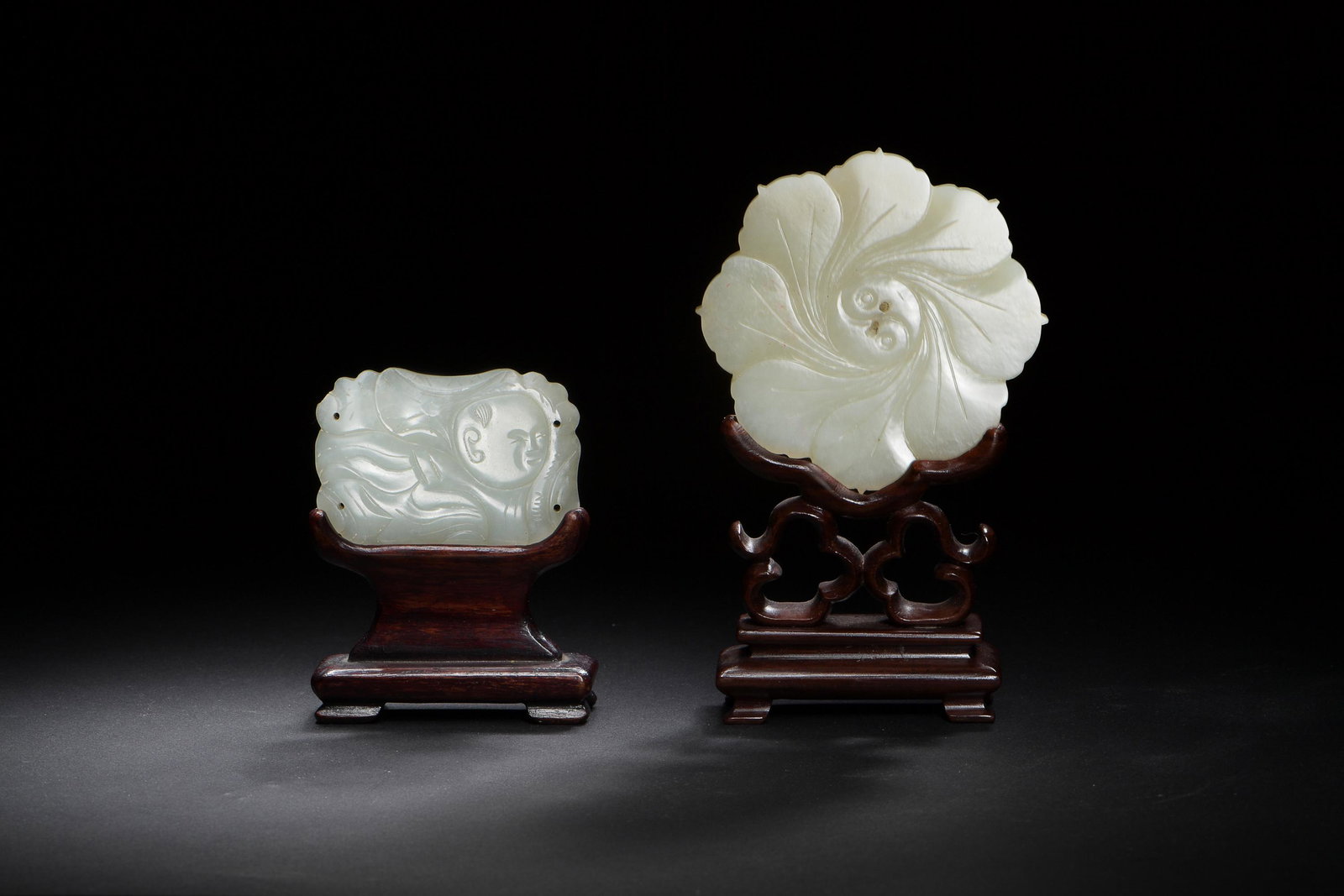 Group of Two Chinese Jade Carvings,19th century: A group of two Chinese jade carvings from the 19th century. One carving features a boy, the other is flower form and features a flower design on one side and a yin-yang symbol on the other. Both carvi