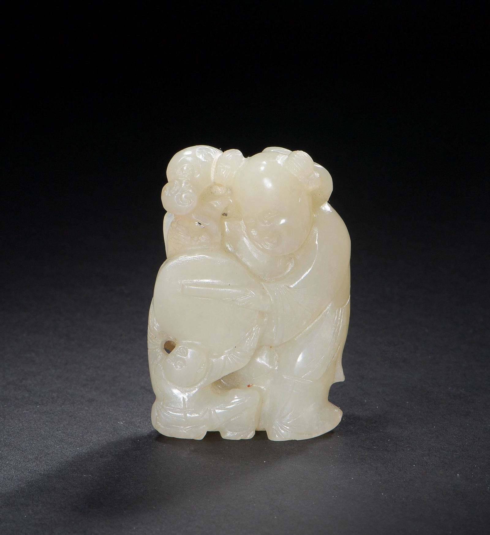Chinese Jade Carved Boy with Drum, 18-19th Century: A Chinese white jade carved toggle dating from the 18th to the 19th century. The toggle features a 2 figures with a drum and lingzhi. Dimensions: 2 inches tall X 1 1/2 inches wide; 5.1 cm tall X 3.8 c