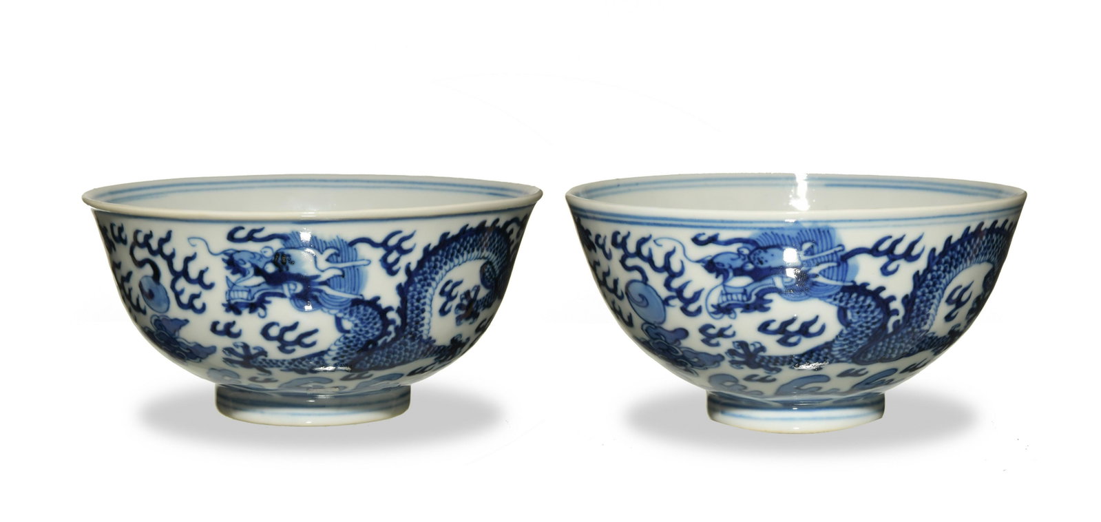 Pair Chinese Blue and White Dragon Bowls, Guangxu: A pair of Chinese blue and white porcelain dragon bowls, each with a 6-character Guangxu mark and of the period. The exterior of each bowl depicts a pair of dragons chasing flaming pearls above a wave