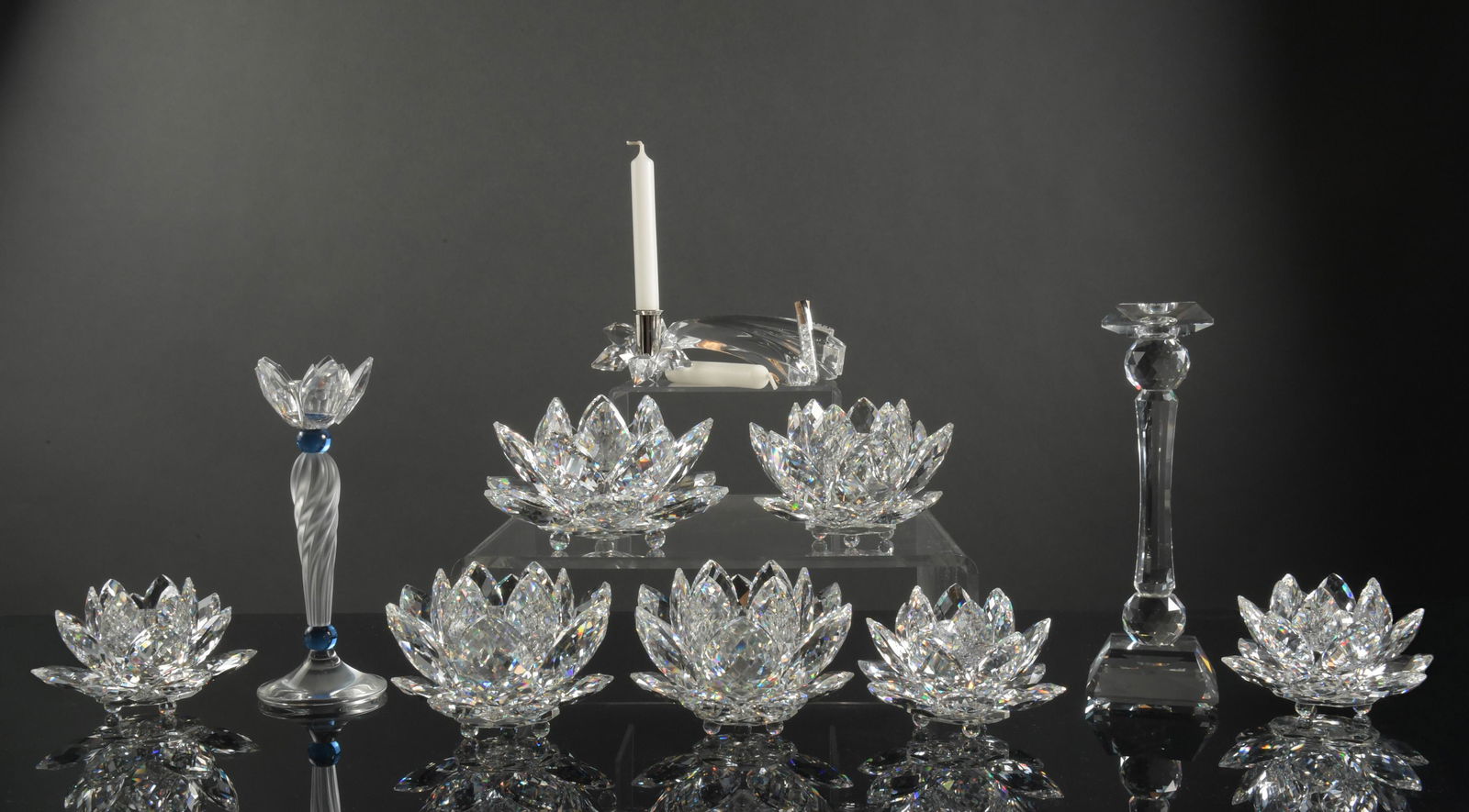 Swarovski, 10 Boxed Crystal Candlesticks and Holders: Swarovski (Austrian, founded 1895) crystal. A group of crystal candle holders. Includes: a shooting star candle holder; a candle stick holder; a blue flower candle stick holder; 3 small water lily can