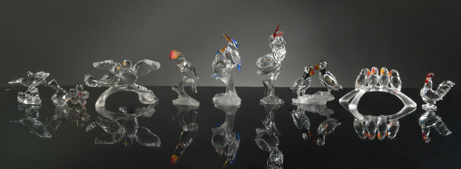 Swarovski, 9 Boxed Crystal Birds Etc.: Swarovski (Austrian, founded 1895) crystal. A group of animals including: a baby bird, a rooster, a dolphin, a pair of puffins, a toucan, a stork with a baby, a pair of kingfishers, baby love birds, a