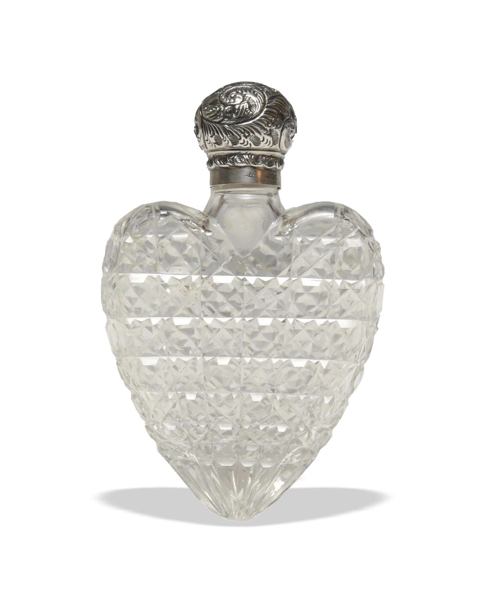 Heart-Form Glass Flask with English Sterling Cap: A Victorian faceted glass heart-form flask with a London hallmarked sterling cap from 1899 by Robert Pringle and Sons. The lid features a vine pattern. Dimensions: 5 1/4 inches tall X 3 3/4 inches wid
