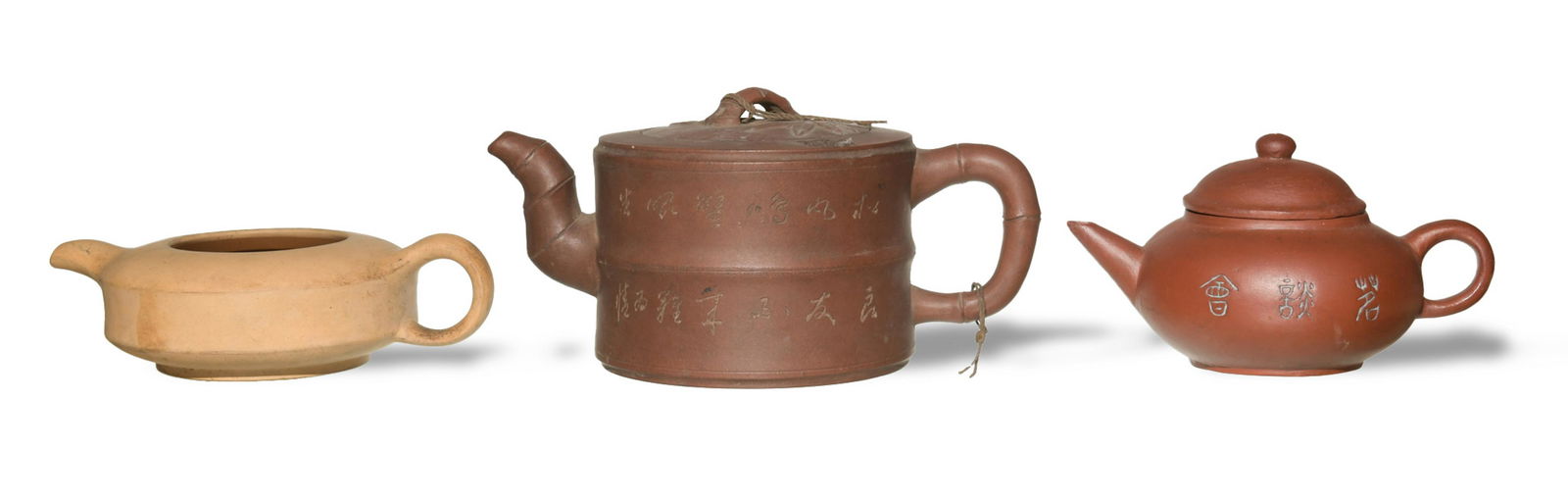 3 Chinese Zisha Teapots: Three Zisha teapots in varied shapes and colors. A small Heng Yun teapot features Chinese calligraphy on one side and has a paper tag on bottom reading "Made in Taiwan." A Tan Duan Ni teapot has a dee
