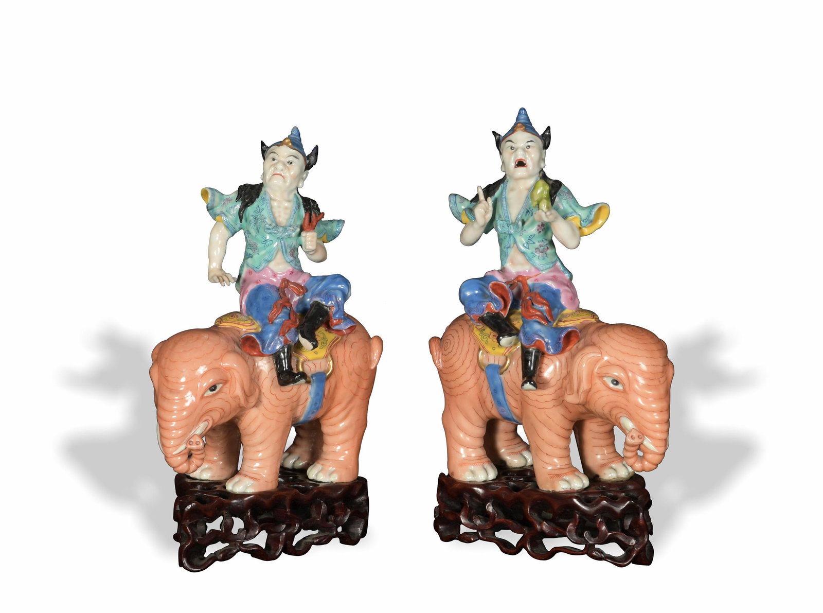 Pair of Chinese Famille Rose Statues, Republic: A pair of Chinese famille rose porcelain statues dating from the Republic period. The lot comes with a pair of wooden stands. Each depicts a mythical figure, possibly a Buddhist yaksha, riding an elep