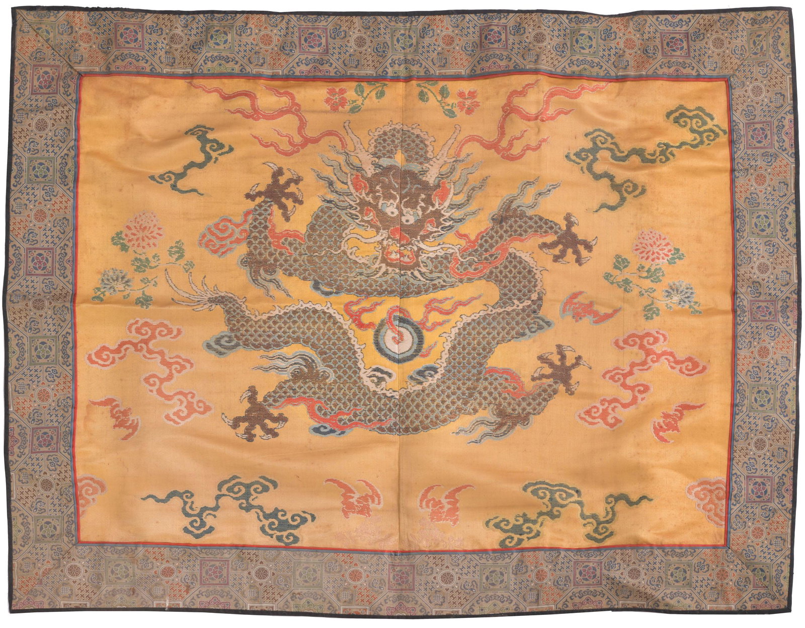 Chinese Yellow Ground Dragon Textile, 18th Century: A Chinese yellow-ground textile with a front-facing dragon dating from the 18th century. The dragon is chasing a flaming pearl. The textile has a green-ground border with geometric patterns. Dimension