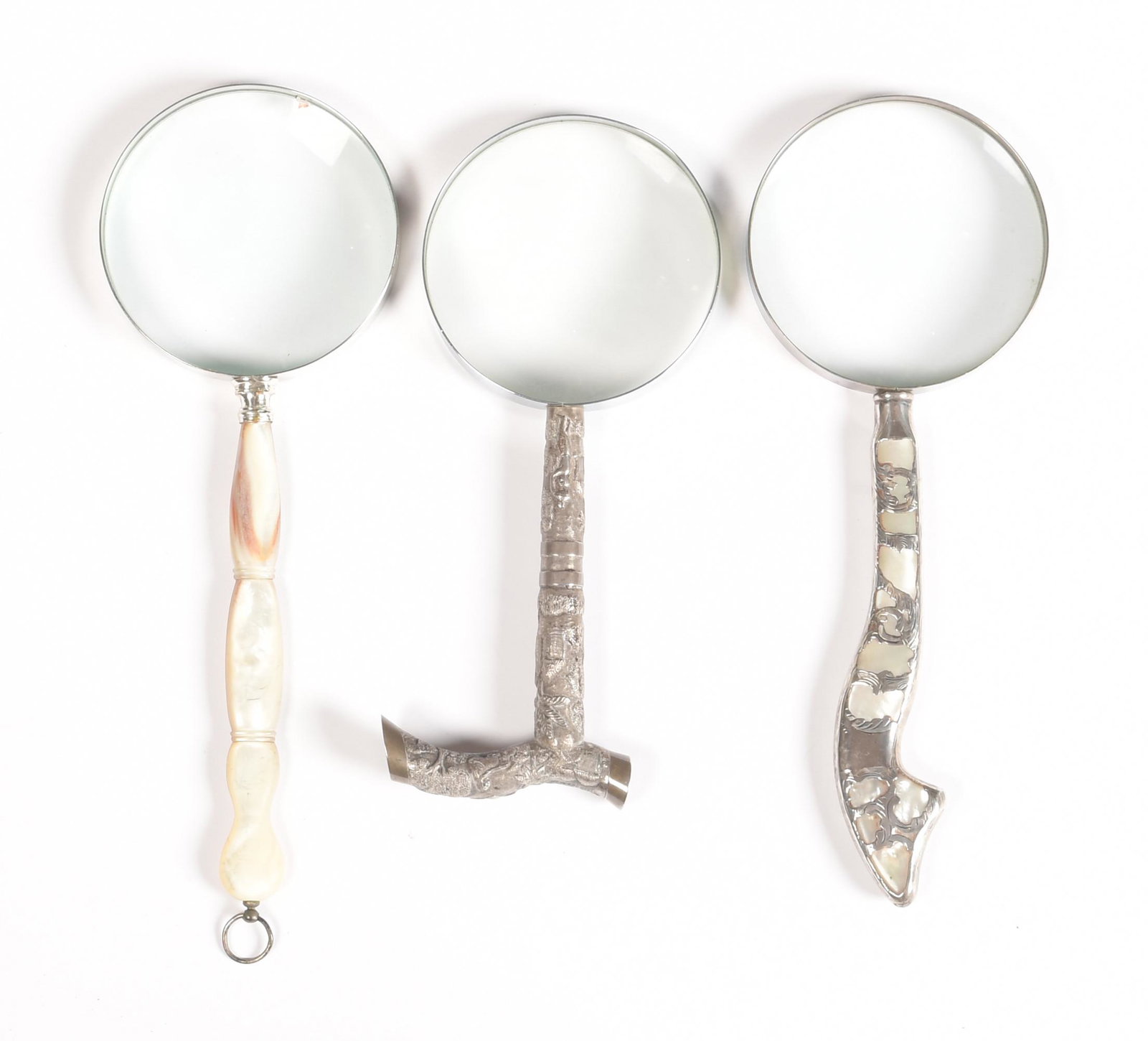 3 Vintage Magnifying Glasses, Sterling and MOP: A lot of three magnifying glasses, one with a Thai or Burmese silver handle, one with Mother of Pearl handle and one with sterling over mother of pearl. Dimensions are: the largest mother of pearl mag