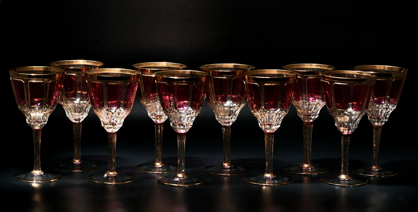 10 Moser Gilt & Cranberry Flashed Stems: A group of 10 Moser gilt and cranberry flashed wine glasses. Dimensions are: 7 1/2 inches tall X 4 inches wide, 19.05 cm X 10.16 cm. All measurements are approximate. Condition: Some minor use wear. O