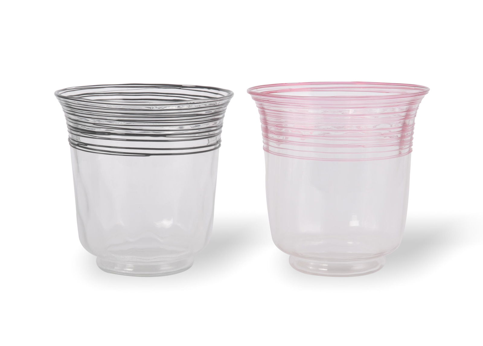 2 Steuben Threaded Glass Ice Buckets: A group of two colorless Steuben ice buckets with colored threads around the lip. One has black threads with a diamond pattern to the body and one has pink threads with a ribbed pattern to the body. B