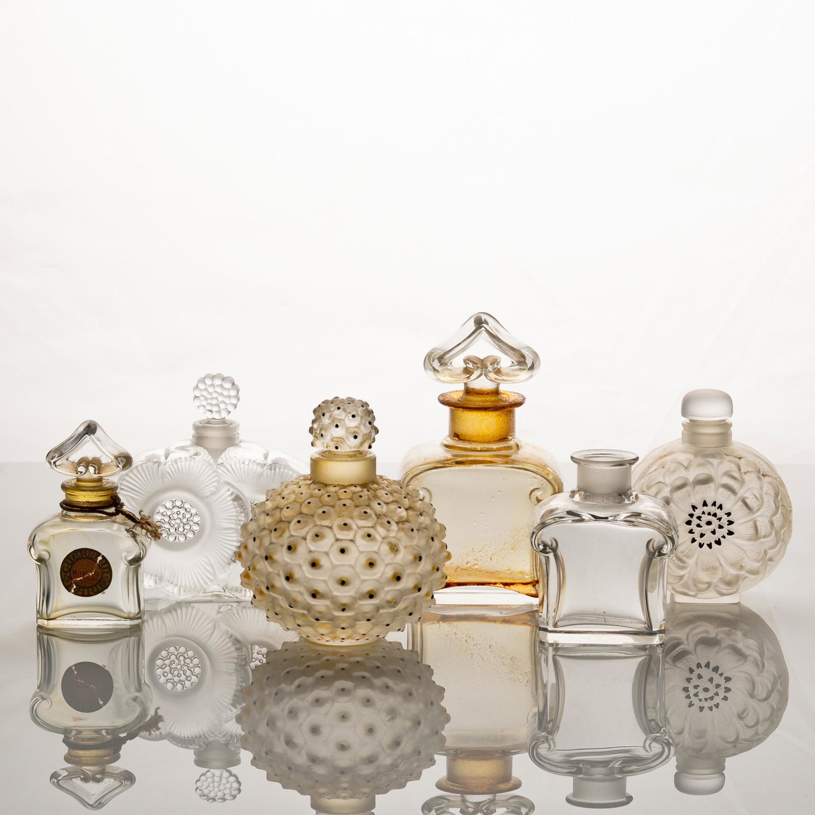 A group of six glass perfume bottles, including three Lalique bottles and two Baccarat bottles. All: A group of six glass perfume bottles, including three Lalique bottles and two Baccarat bottles. All bottles are marked. Dimensions are: the largest Baccarat bottle including the stopper measures 4 1/4