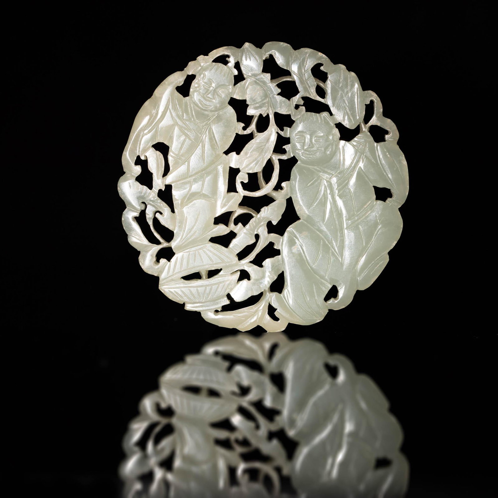 A Chinese white jade round plaque, 19th century: A Chinese white jade round plaque 19th century Featuring Hehe Erxian. H: 2 1/2, W: 2 1/2, D: 1/8 in. H: 6.35, W: 6.35, D: 0.32 cm. All measurments are approximate. Provenance: From Mrs. Hillebrand in 