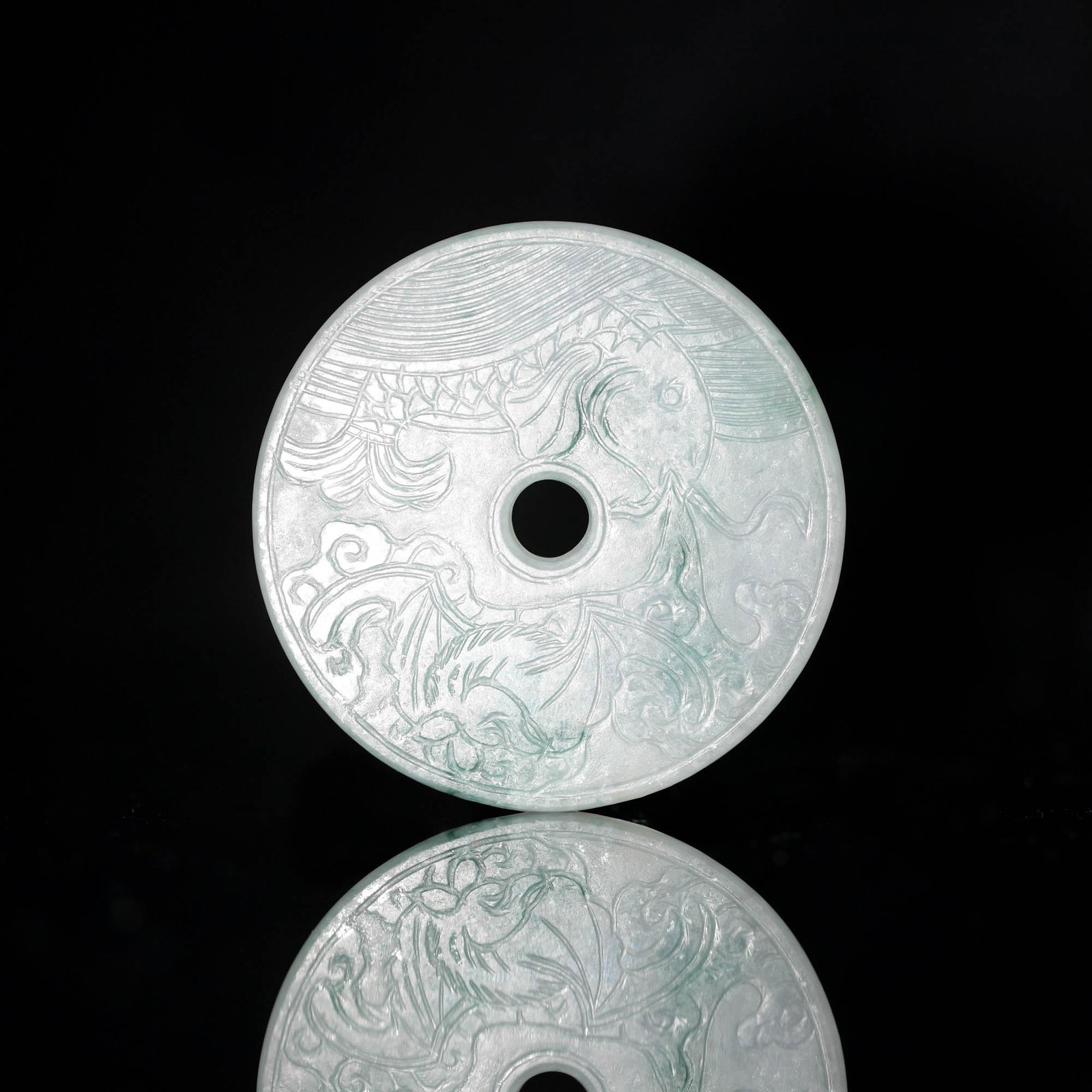 A Chinese carved jadeite bi, 19th century: A Chinese carved jadeite bi 19th century H: 1/4, Dia: 2 3/8 in. H: 0.64, Dia: 6.0 cm. All measurments are approximate. Provenance: From Mrs. Hillebrand in Chicago, Illinois. Her father-in-law purchase