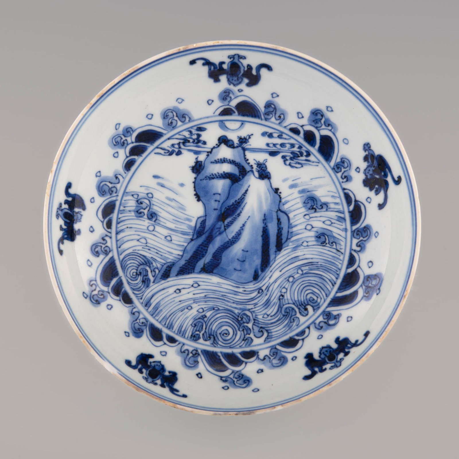 A Chinese blue and white plate, Yongzheng period: A Chinese blue and white plate Yongzheng period With a scene of waves crashing against a rocky cliff to the interior, surrounded by five bats; six-character mark to underside. H: 1 3/8, Dia: 6 1/4 in.