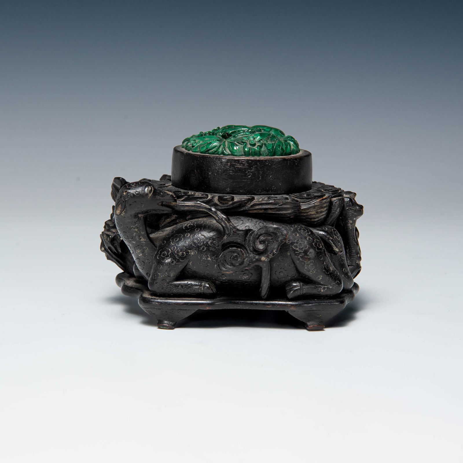 A Chinese carved wooden deer with malachite inlay, 19th century: A Chinese carved wooden deer with malachite inlay 19th century Featuring a sitting deer with ruyi clouds protruding from the mouth, topped with malachite inlay carved with floral and vegetal motifs. H