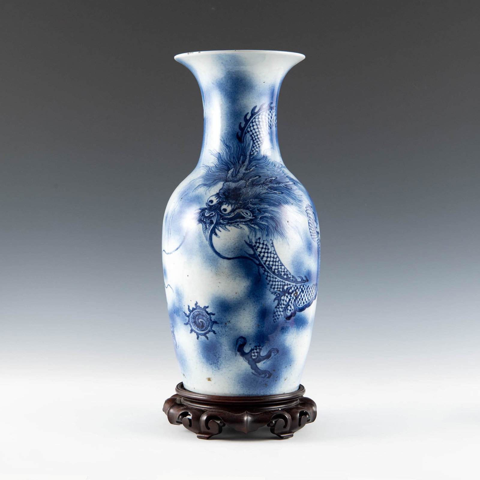 A Chinese blue and white dragon vase, 19th century: A Chinese blue and white dragon vase 19th century Featuring 'dragons chasing a flaming pearl' motif to exterior. Sold with associated wood stand. H: 17 3/4, Dia: 8 3/4 in. H: 45.09, Dia: 22.23 cm. (va