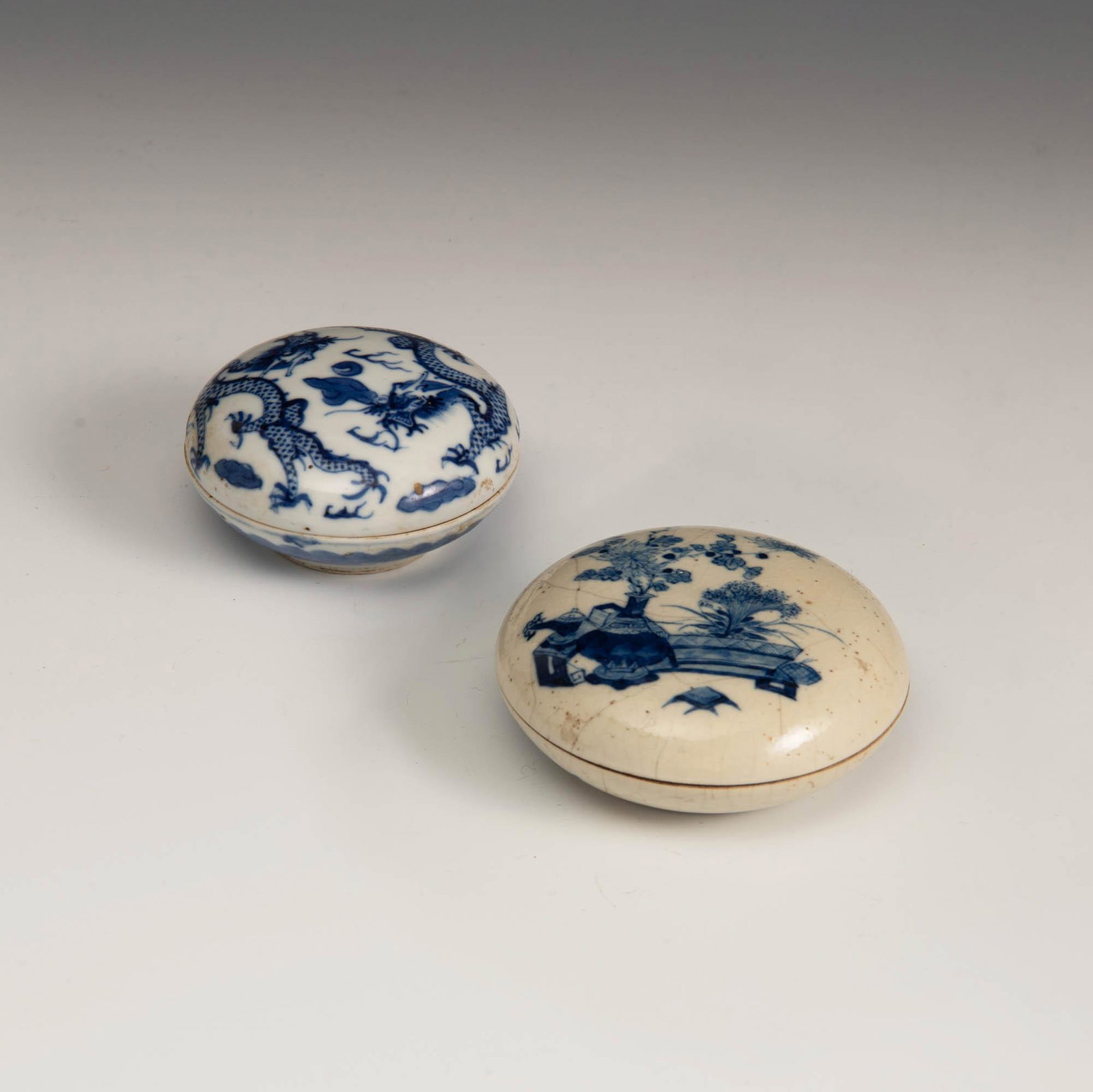 Two Chinese blue and white porcelain seal boxes, 19th century: Two Chinese blue and white porcelain seal boxes 19th century The smaller featuring dragons with four-character mark to underside, the larger featuring scholarâ€™s items with six-character mark to