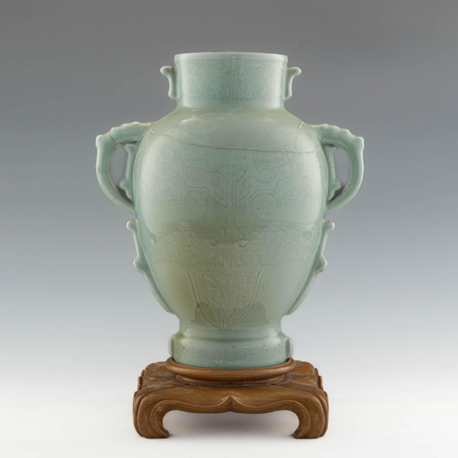 A Chinese Longquan-style celadon vase, 18th century: A Chinese Longquan-style celadon vase 18th century Featuring multiple registers of taotie mask motifs with large beast-form handles. With six-character mark to underside. Sold with associated wooden s
