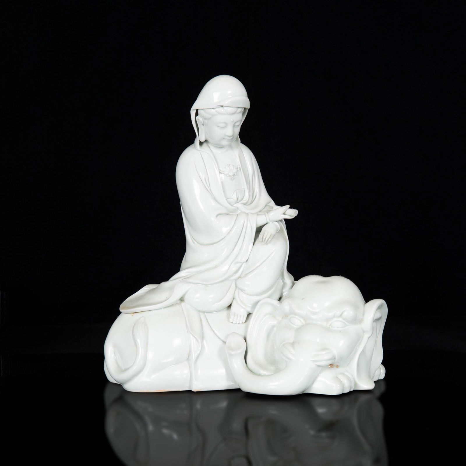 A Chinese Dehua blanc-de-chine Guanyin, early 20th century: A Chinese Dehua blanc-de-chine Guanyin early 20th century Guanyin in flowing robes seated on elephant delicately holding scroll and wearing lotus necklace. With four-character mark to back of Guanyin.