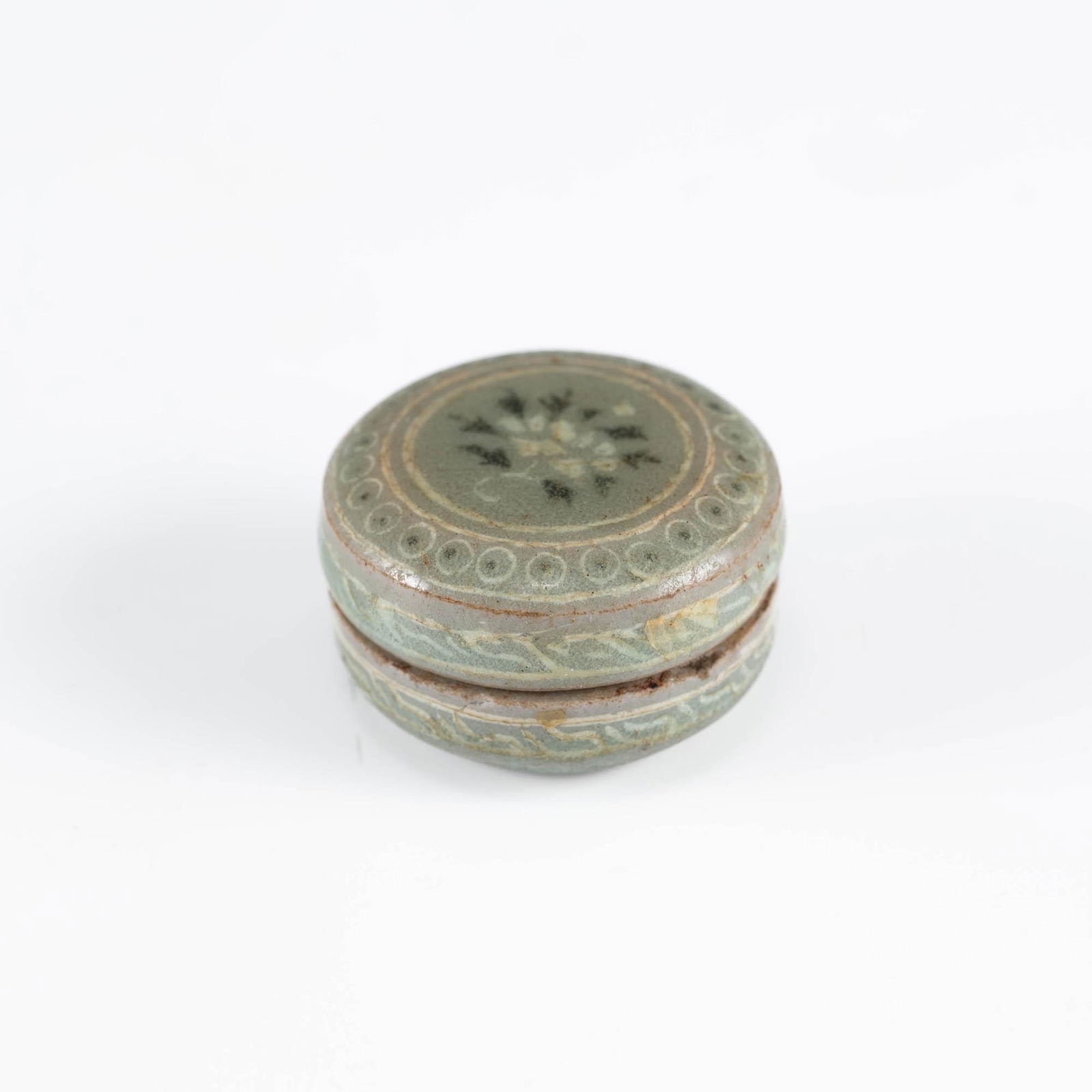 A miniature Korean celadon seal box, Joseon period: A miniature Korean celadon seal box Joseon period With bands of decorative geometric motifs. H: 7/8, Dia: 1 3/8 in. H: 2.22, Dia: 3.49 cm. Provenance: Private collection, Los Angeles, California. <br