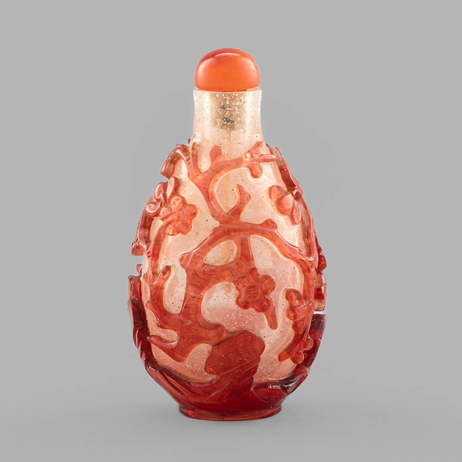A Chinese red on white Peking glass snuff bottle, 19th century: A Chinese red on white Peking glass snuff bottle 19th century Transparent white-ground glass bottle with red flowering branch motifs throughout. H: 3, W: 1 1/2 in. H: 7.62, W: 3.81 cm. Provenance: Mrs
