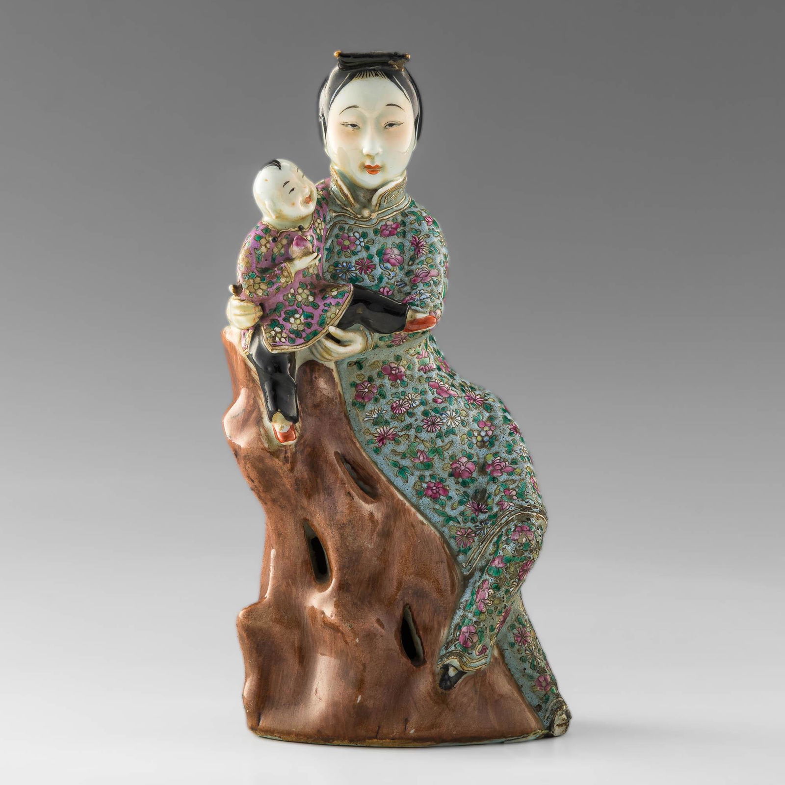 A Chinese famille rose statue of a court lady, Republic period: A Chinese famille rose statue of a court lady Republic period An elegant lady dressed in blue-ground flower robes seated on a rock holding a young boy with peach. H: 9 1/4, W: 4 5/8, D: 3 1/4 H: 23.49