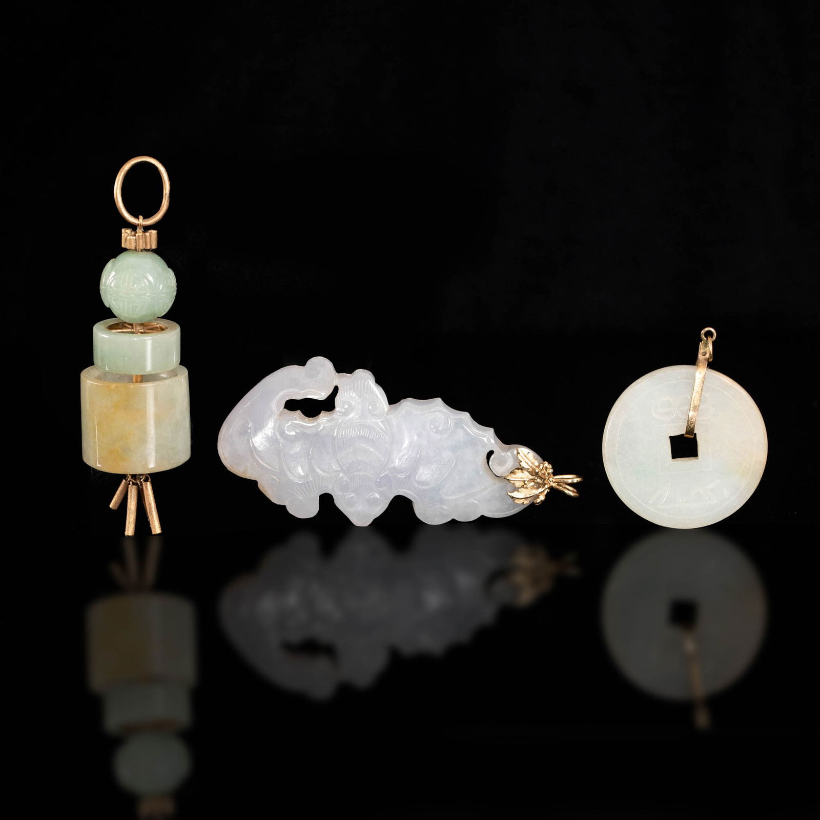 Three Chinese carved jadeite toggles, 19th century: Three Chinese carved jadeite toggles 19th century Comprising a Daoguang tongbao-shaped toggle; a bat toggle; and a three-tiered jade and gilt-metal toggle. All with jewelry loops. (3). H: 4, W: 1 3/4,