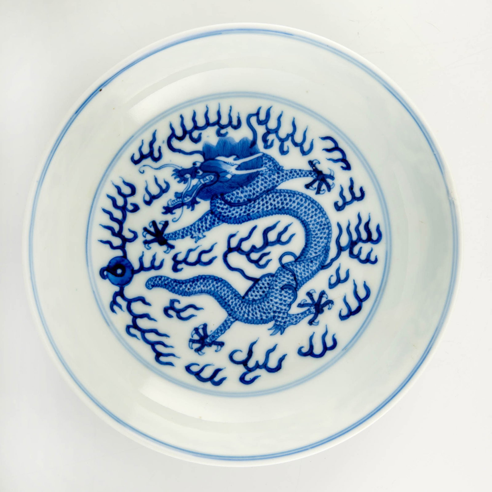 A Chinese blue and white 'dragon' plate, Guangxu period, Qing dynasty: A Chinese blue and white 'dragon' plate Guangxu period, Qing dynasty Featuring 'dragon chasing a flaming pearl' motif to interior and exterior. With six-character Guangxu mark to underside. Sold with 
