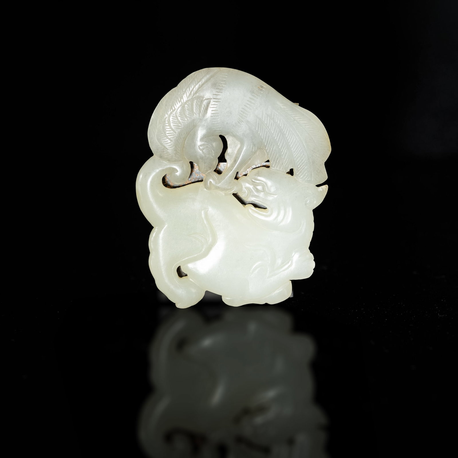 A Chinese carved jade 'beast' plaque, 18th century: A Chinese carved jade 'beast' plaque 18th century Carved to both sides appears a rearing qilin with phoenix perched on its back. Sold with associated textile pouch. H: 2 5/8, W: 2 1/8, D: 1/4 in. H: 6