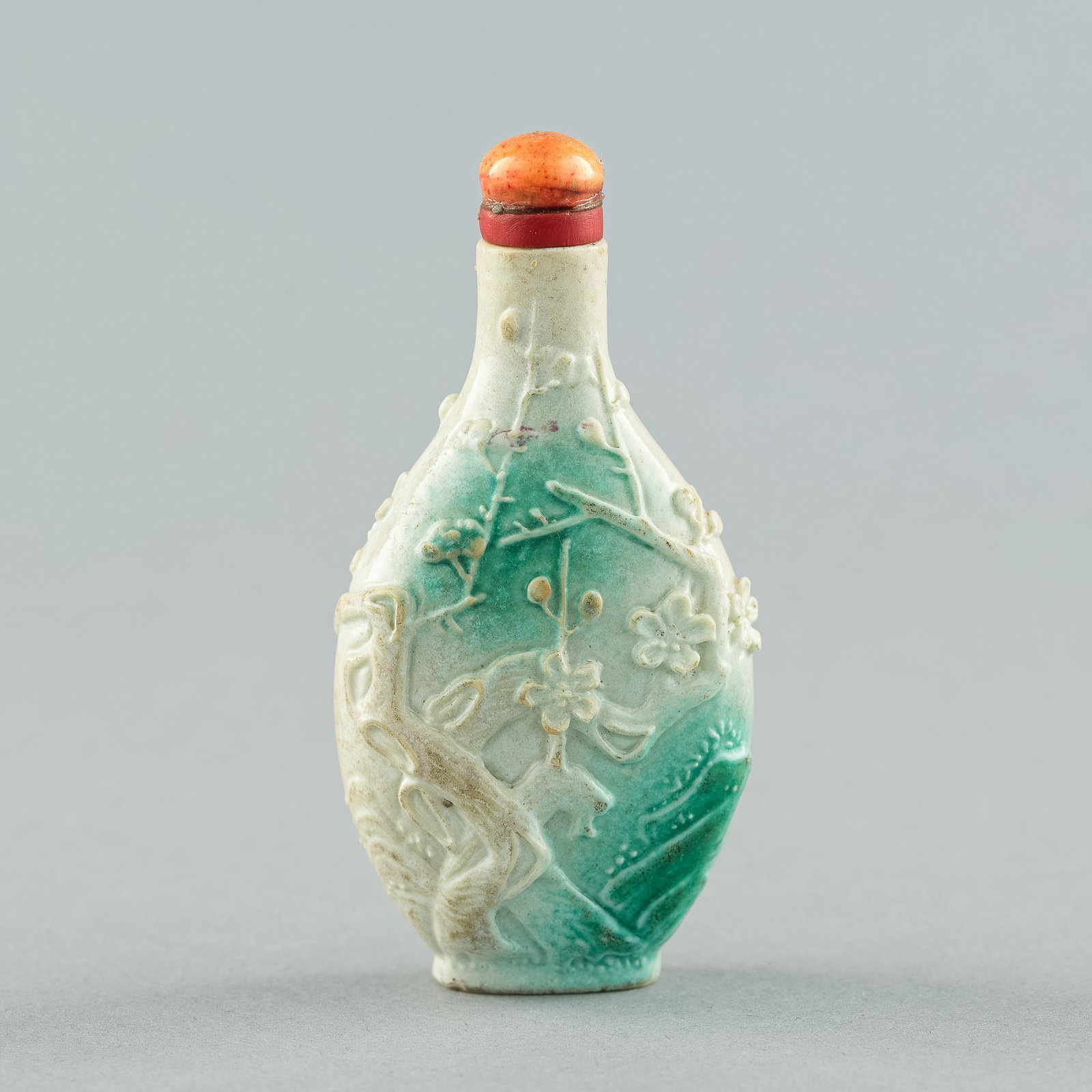 A Chinese porcelain imitation-jadeite snuff bottle, 19th century: A Chinese porcelain imitation-jadeite snuff bottle 19th century Featuring 'plum blossom' motifs throughout. H: 2 1/2, W: 1 3/8 in. H: 6.35, W: 3.49 cm. Private collection, Powder Springs, Georgia.