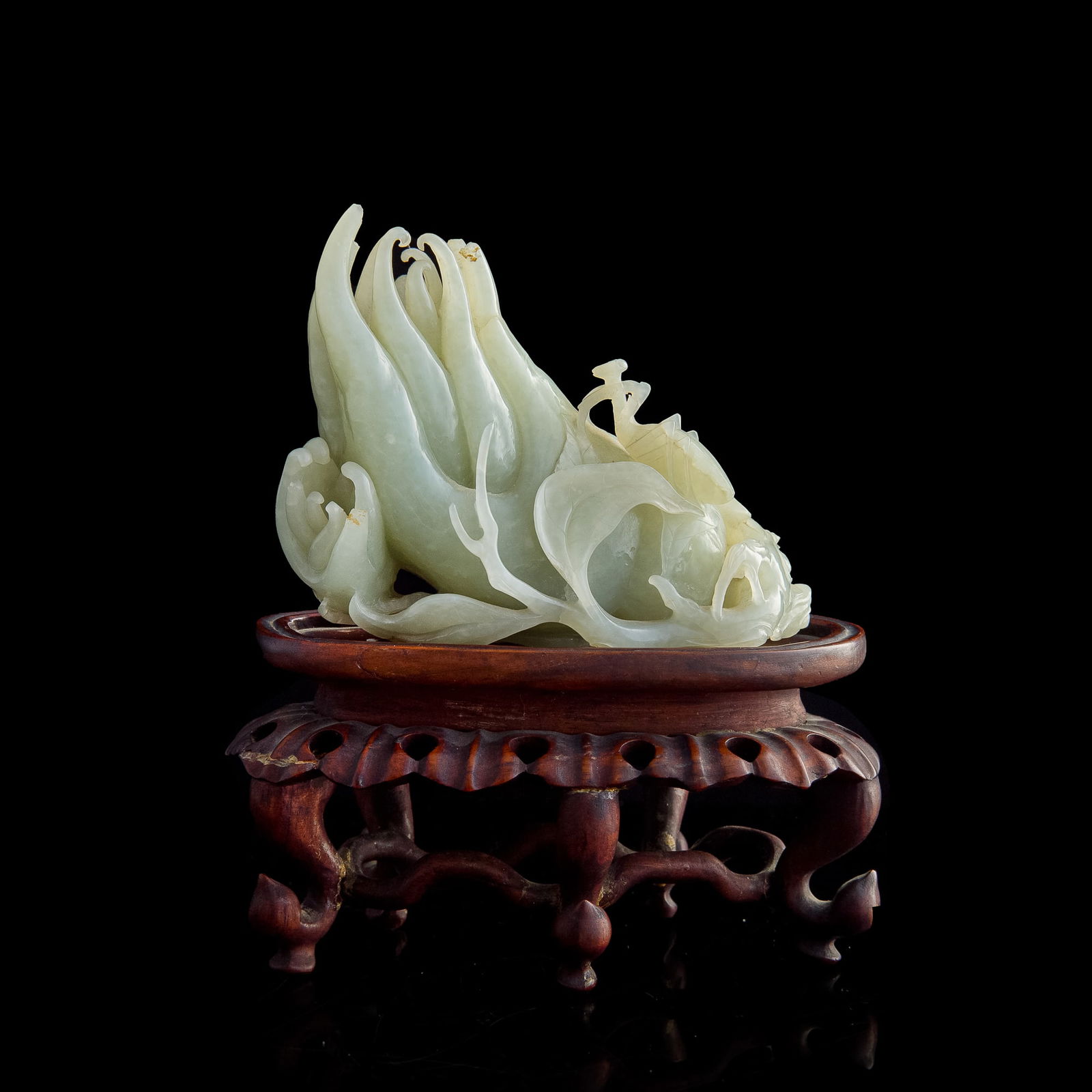 A Chinese carved jade Buddha's hand fruit, 18th century: A Chinese carved jade Buddha's hand fruit 18th century A praying mantis crawls up the side of the fruit. Sold with one associated hardwood stand. H: 4 1/4, W: 5 1/8, D: 2 1/2 in. (H: 10.80, W: 13.02,